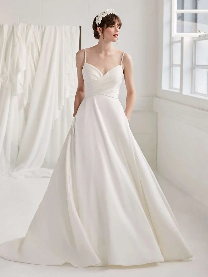 ✨ Size 12/14 ✨

A classic Mikado a-line style, with a gently pleated bodice, finished with delicate pearl beaded straps. She&rsquo;s finished with a statement removable bow, and of course, pockets!! 

Designer - Ellis Bridals