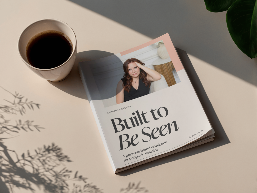 A book titled "Built to Be Seen" with a woman on the cover, a cup of coffee, and a green plant on a light table with shadows and a natural light source.