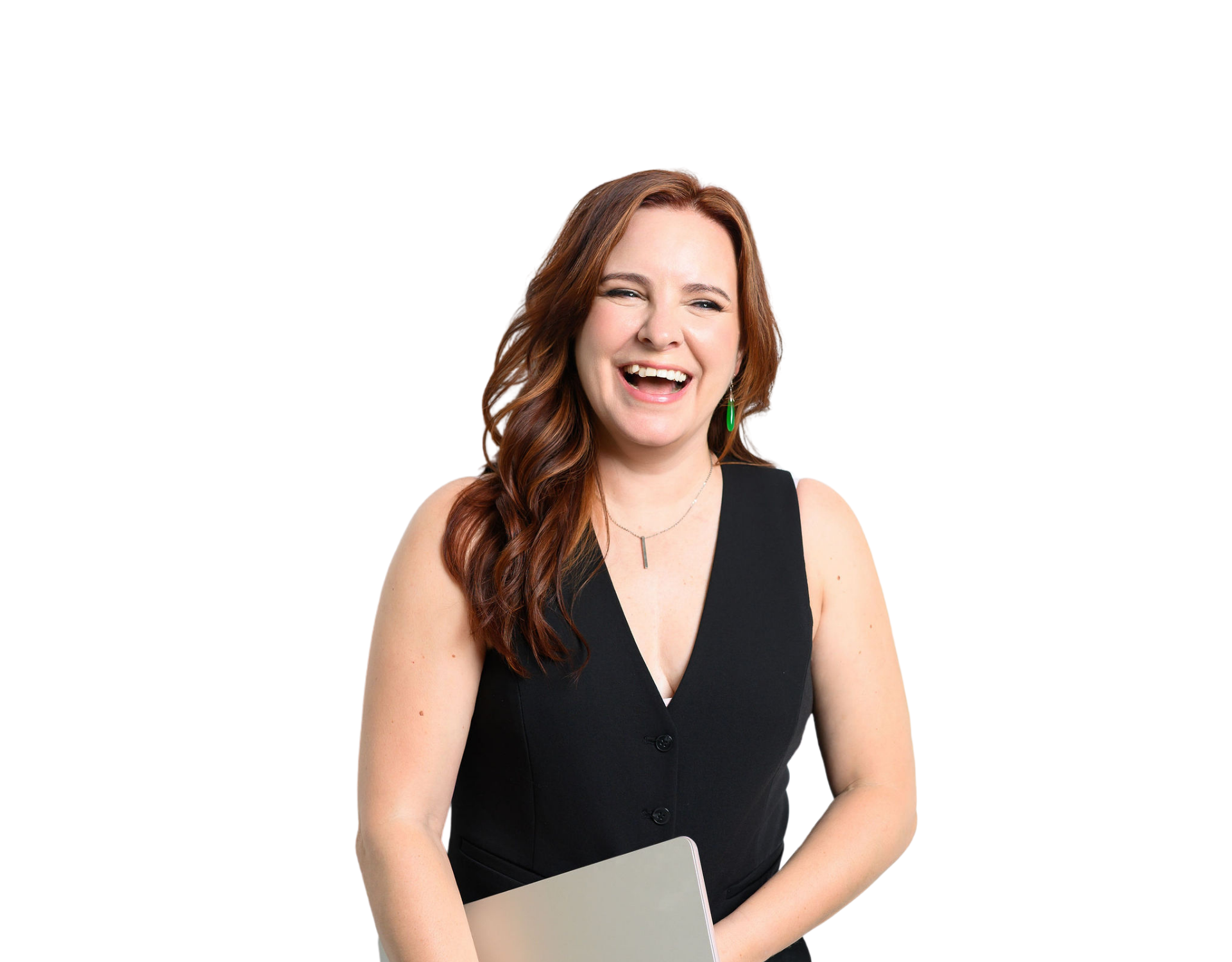 A woman with long, wavy, reddish-brown hair, wearing a black sleeveless blazer, green earrings, and a silver necklace, laughing and holding a silver laptop.