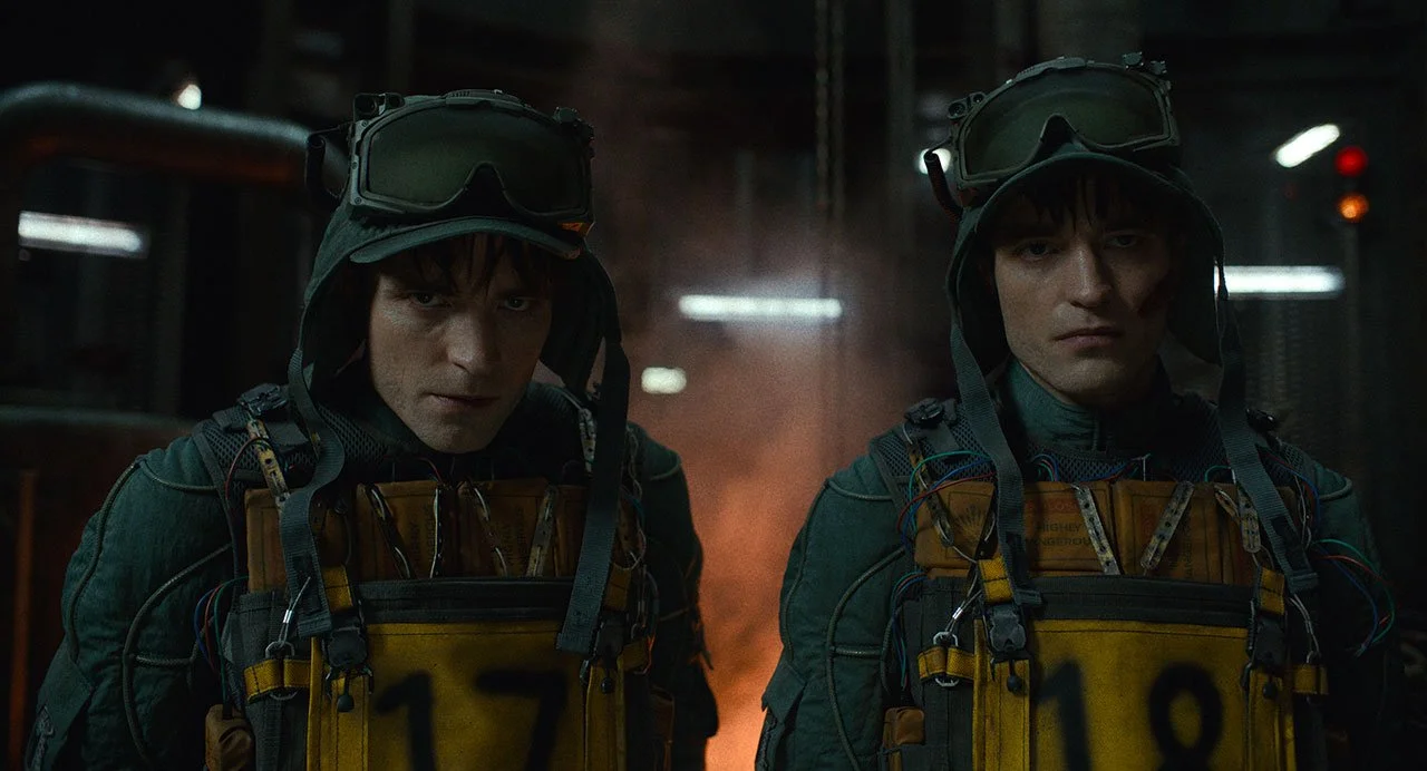 Two men in tactical gear, wearing goggles on their heads, standing in a dim, industrial setting with a fiery glow in the background. DILLIES