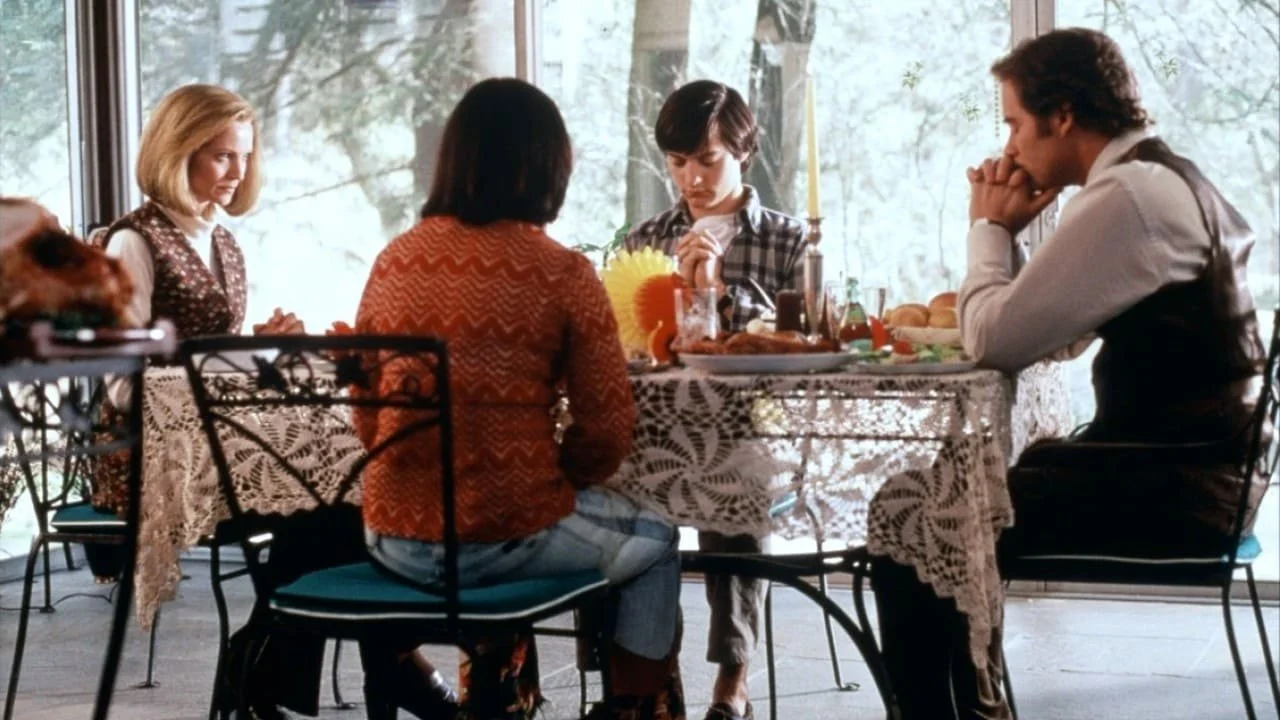 Family gathered around a dining table for a meal, with a woman reading a Bible and praying before eating.
