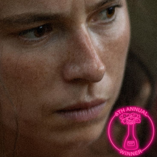 A woman with closed eyes, wearing a black beanie and headphones, sleeping on a bus or train at night with city lights and a sunset visible through the window. A circular award badge in the bottom right corner indicates she is a winner of the 5th Annual Dillweed Society Excellence in Film Awards.