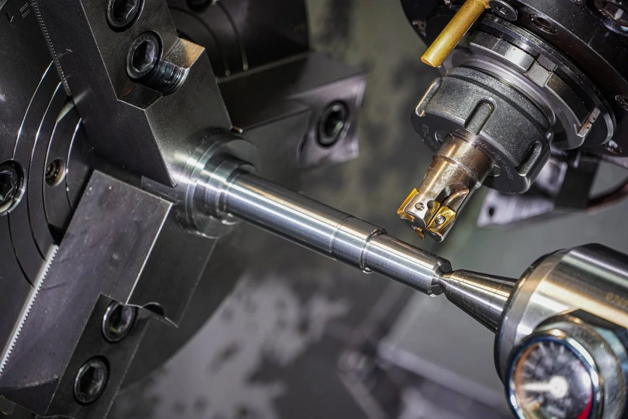Close-up of a metal lathe machine cutting a cylindrical metal workpiece.