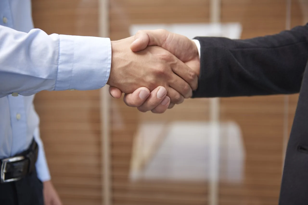 Close-up of two people shaking hands in a professional setting.