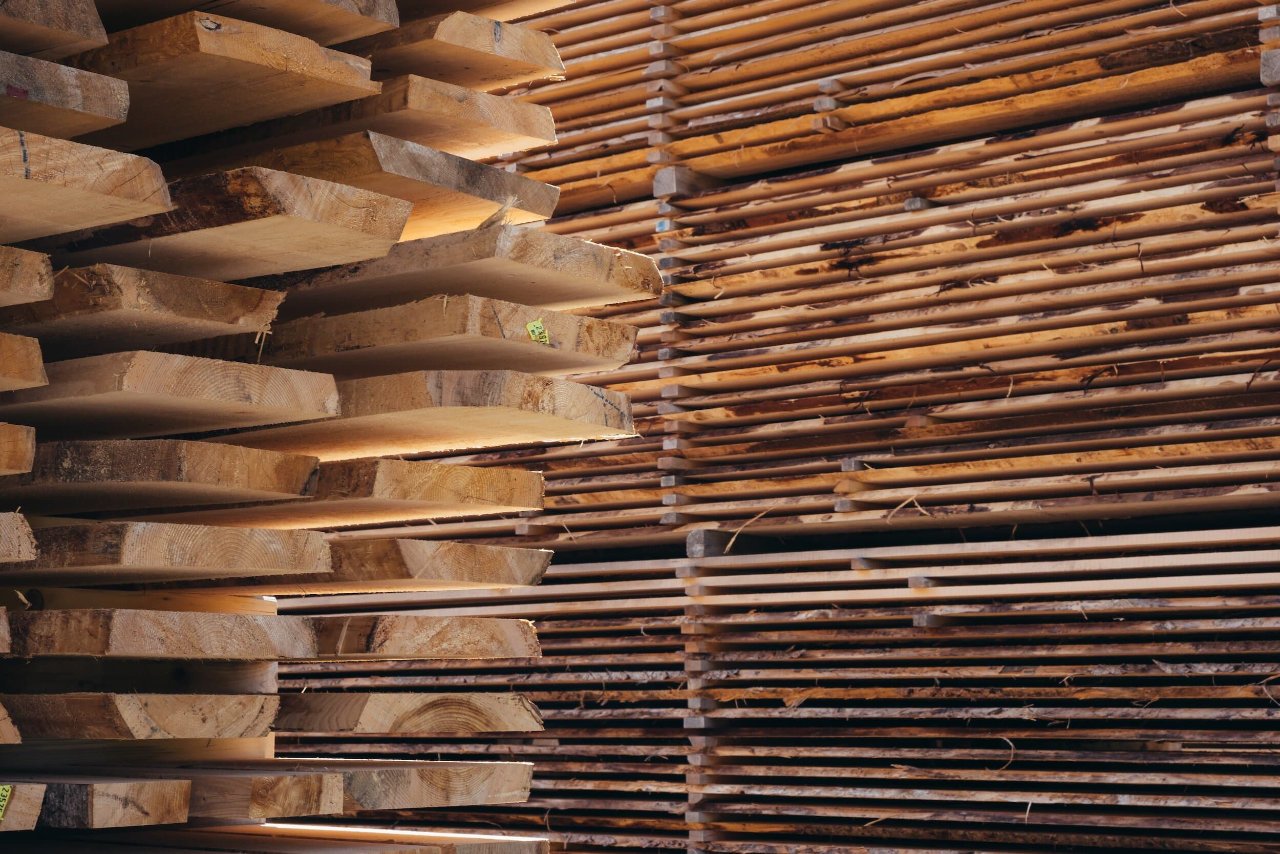 Stacks of cut wooden planks and bamboo poles stored in a warehouse or lumber yard.