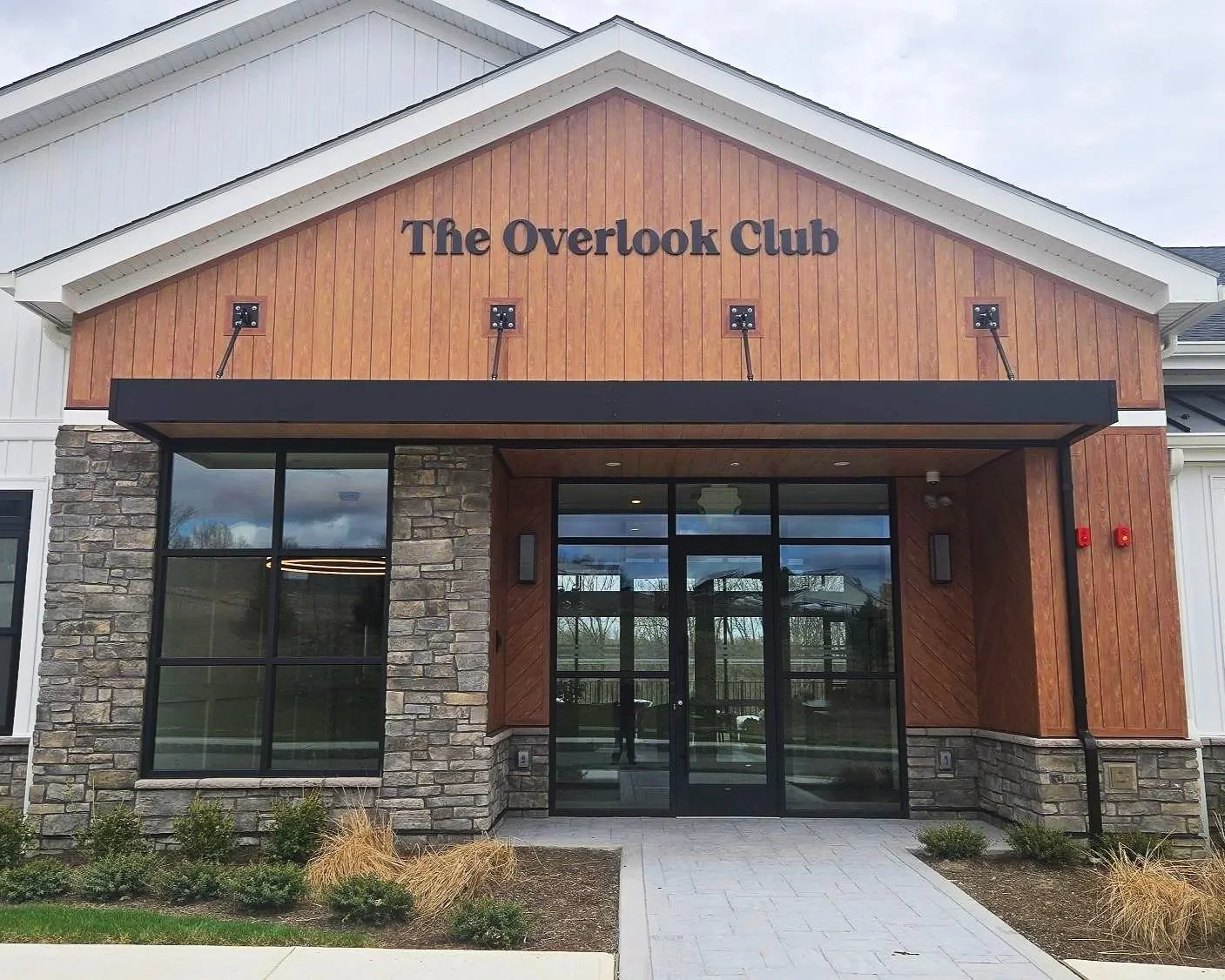 Classy lettering reading The Overlook Club in the front of a wood and stone covered building.