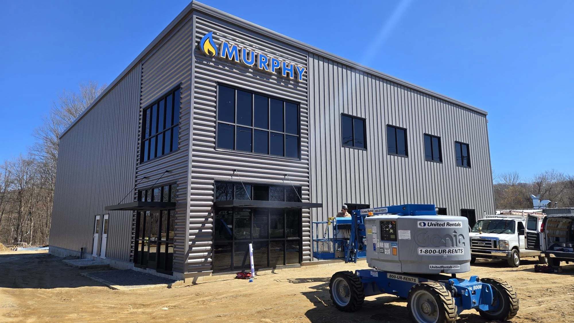 Murphy heating and cooling sign finished and final installation on the side of a grey square modern looking warehouse building with a crane parked in front