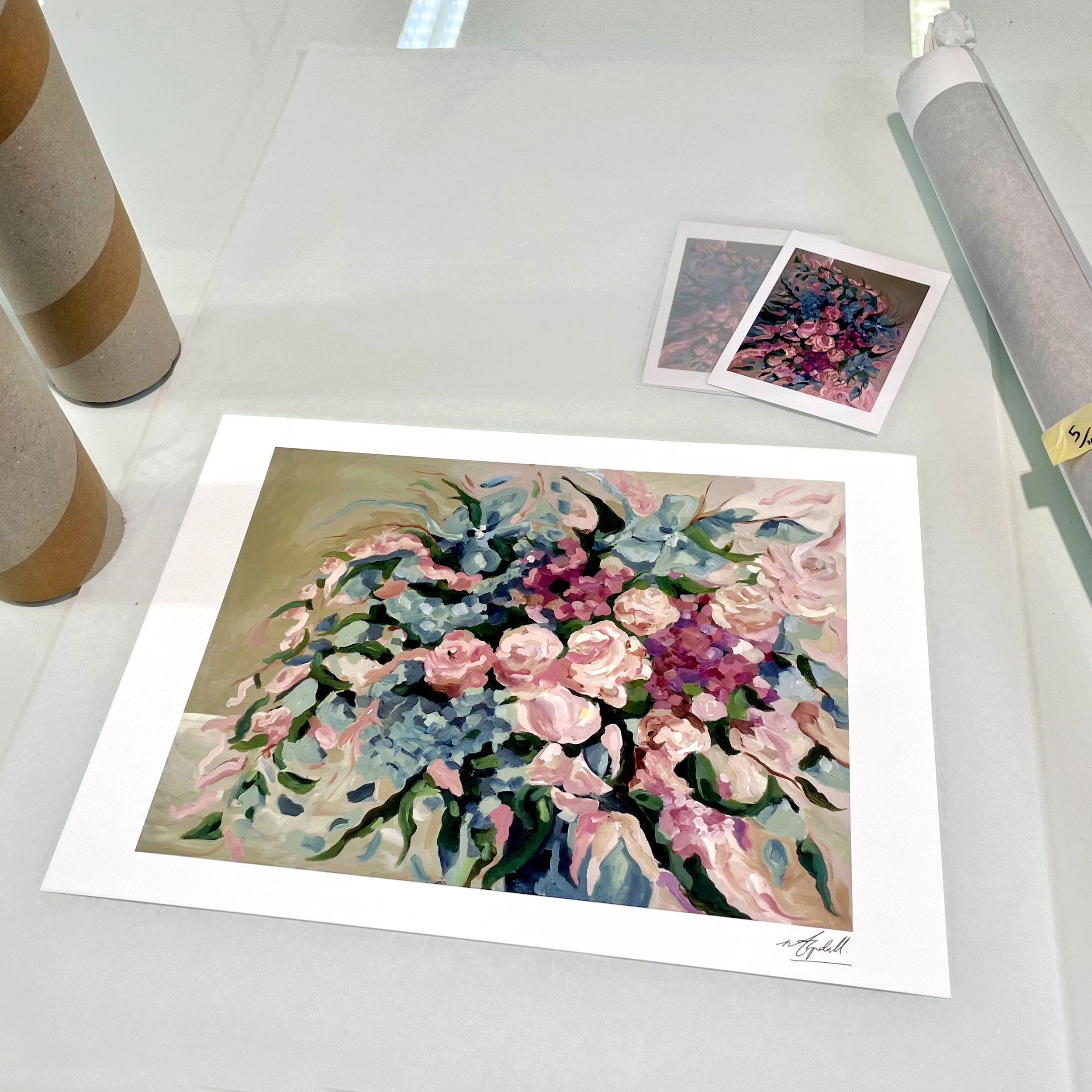 A floral painting with pink, white, and dark blue flowers, signature at the bottom right, set on a white background.