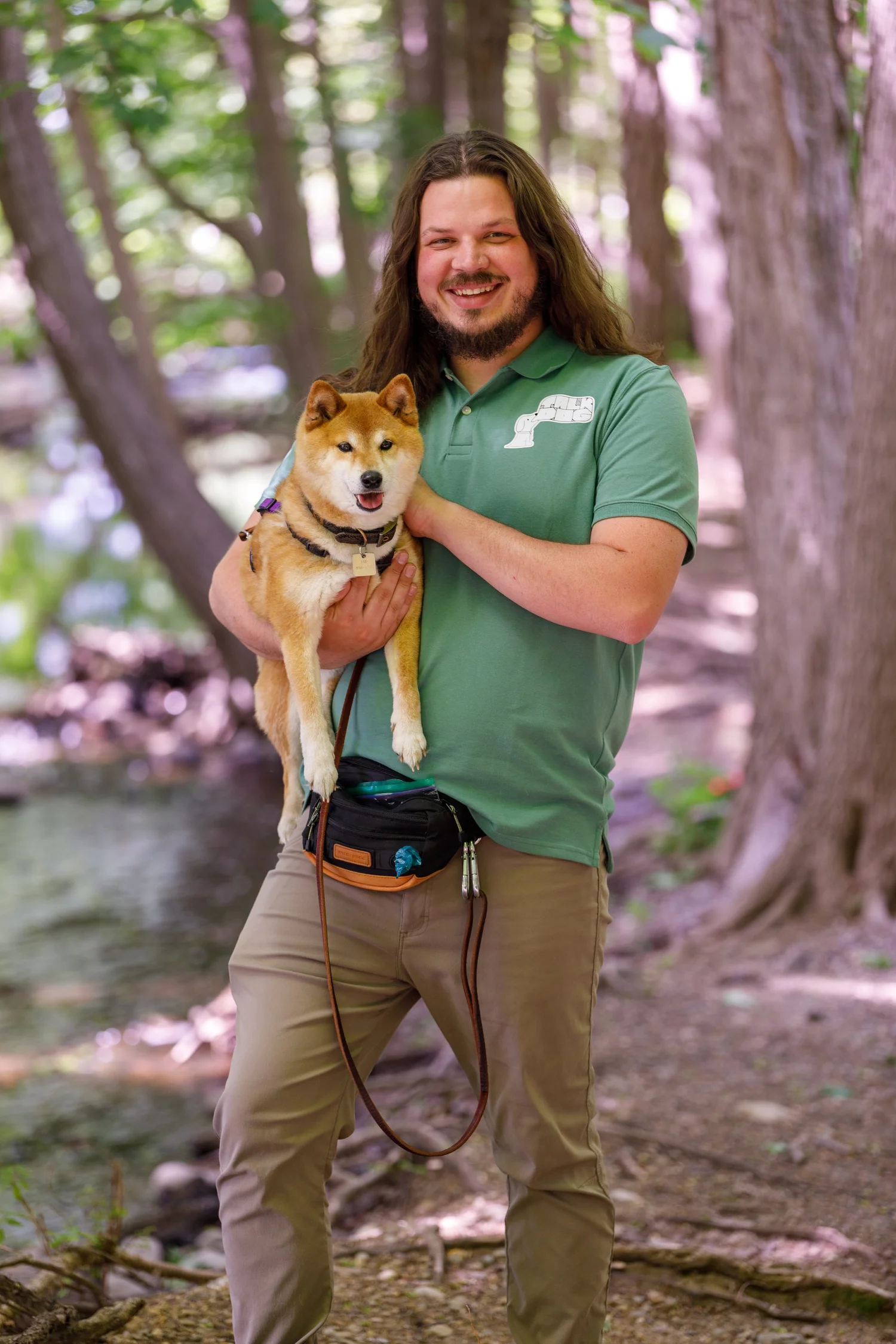 Austin Simmons holding a dog during a TalkDog training session outdoors