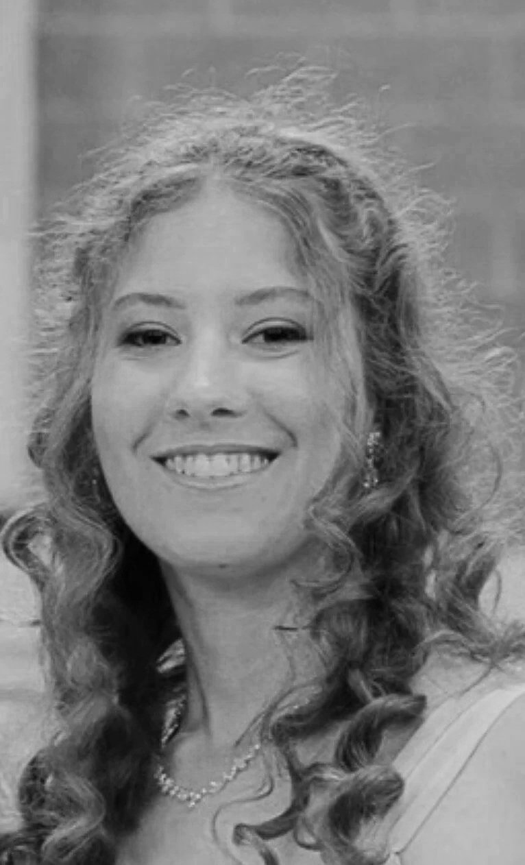 A female therapist Alayna Patrick with curly hair smiling for the camera in a grayscale photo.