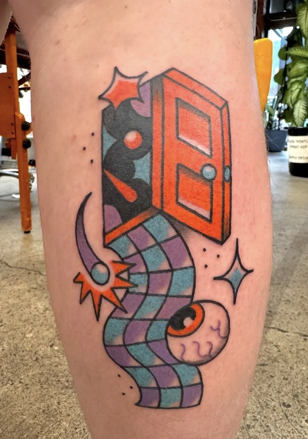 Colorful tattoo featuring a geometric door, a moon, stars, and a cosmic scene with an abstract, rainbow-colored background.