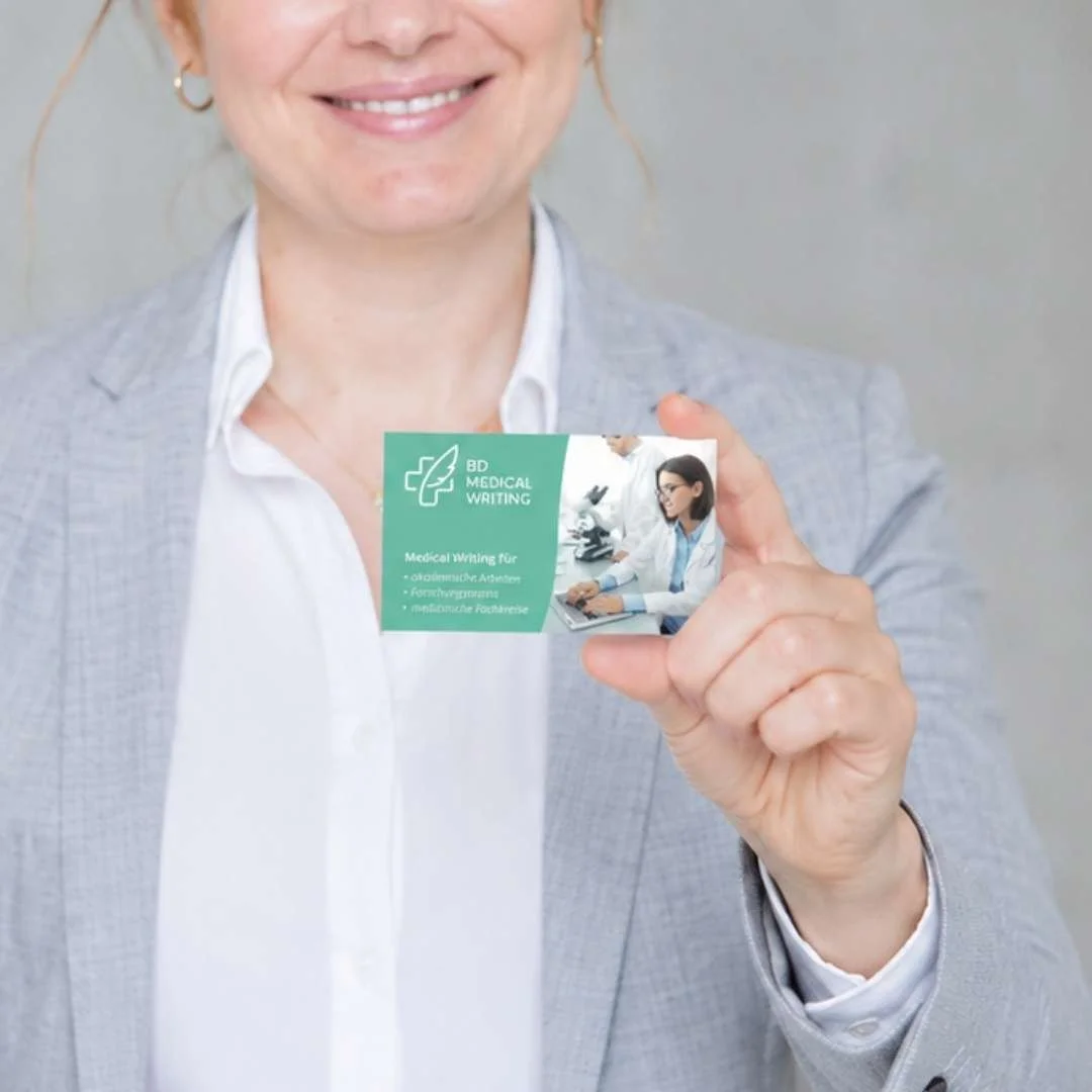 Person hält eine Visitenkarte im Corporate Design von BD Medical Writing in der Hand
