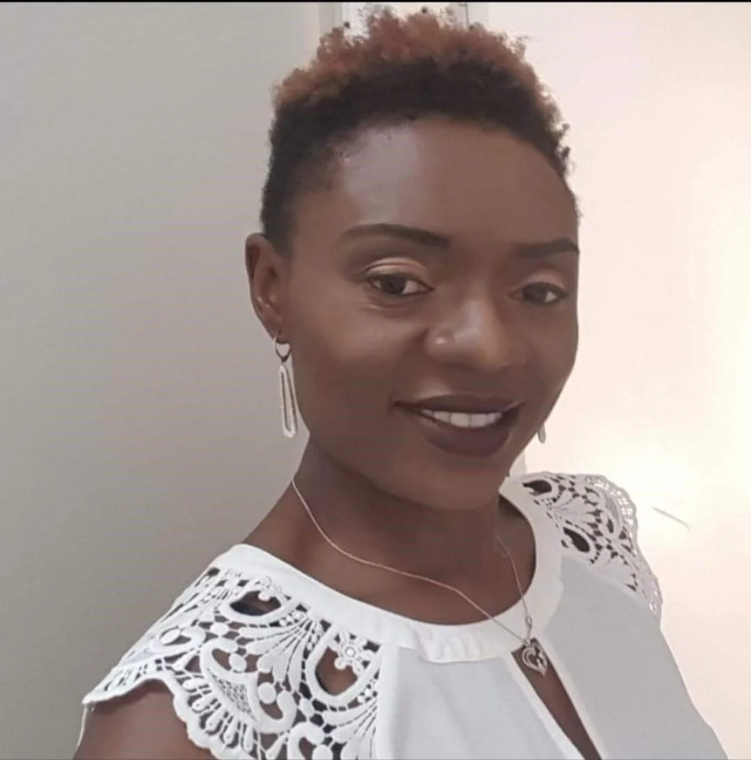 Rosalind Ekema smiling wearing a white top with lace sleeves, earrings, and a necklace.
