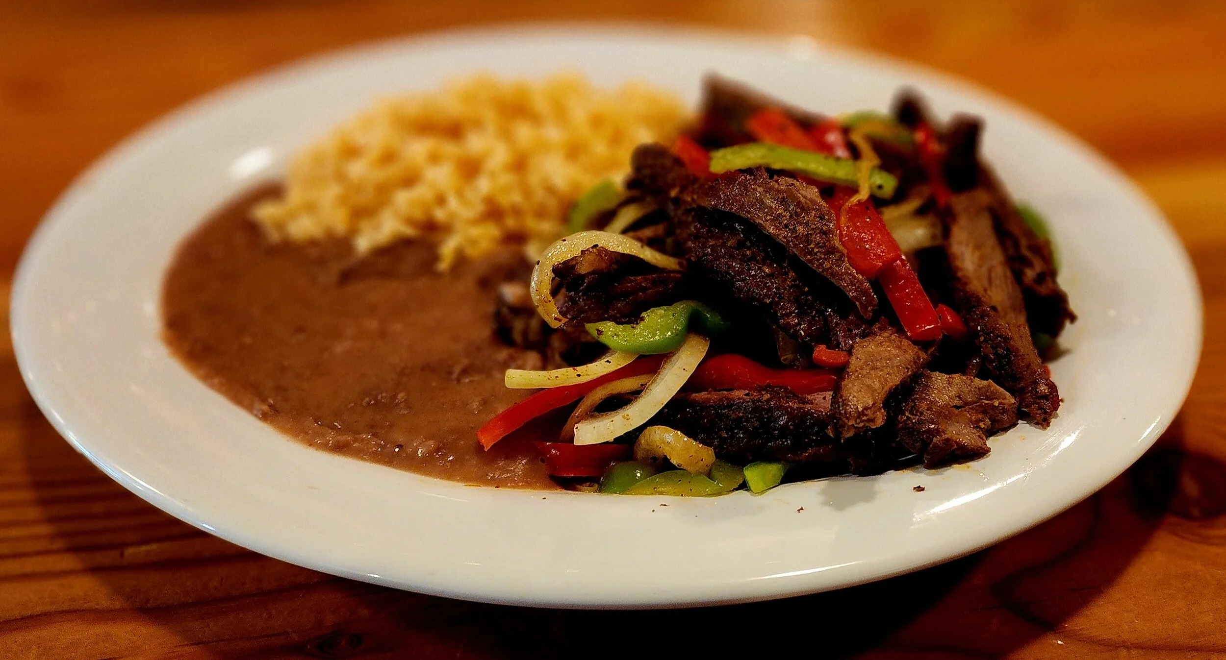 Plate of Mexican food with Fajita's, rice, and bean's 