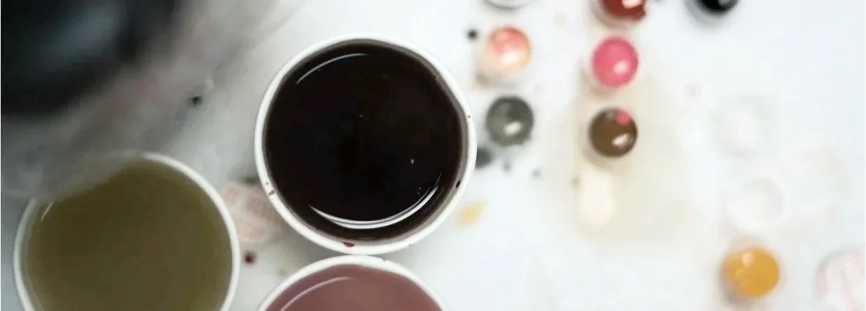 Cups of multi colored ink and paint water. Tattoo artists station.