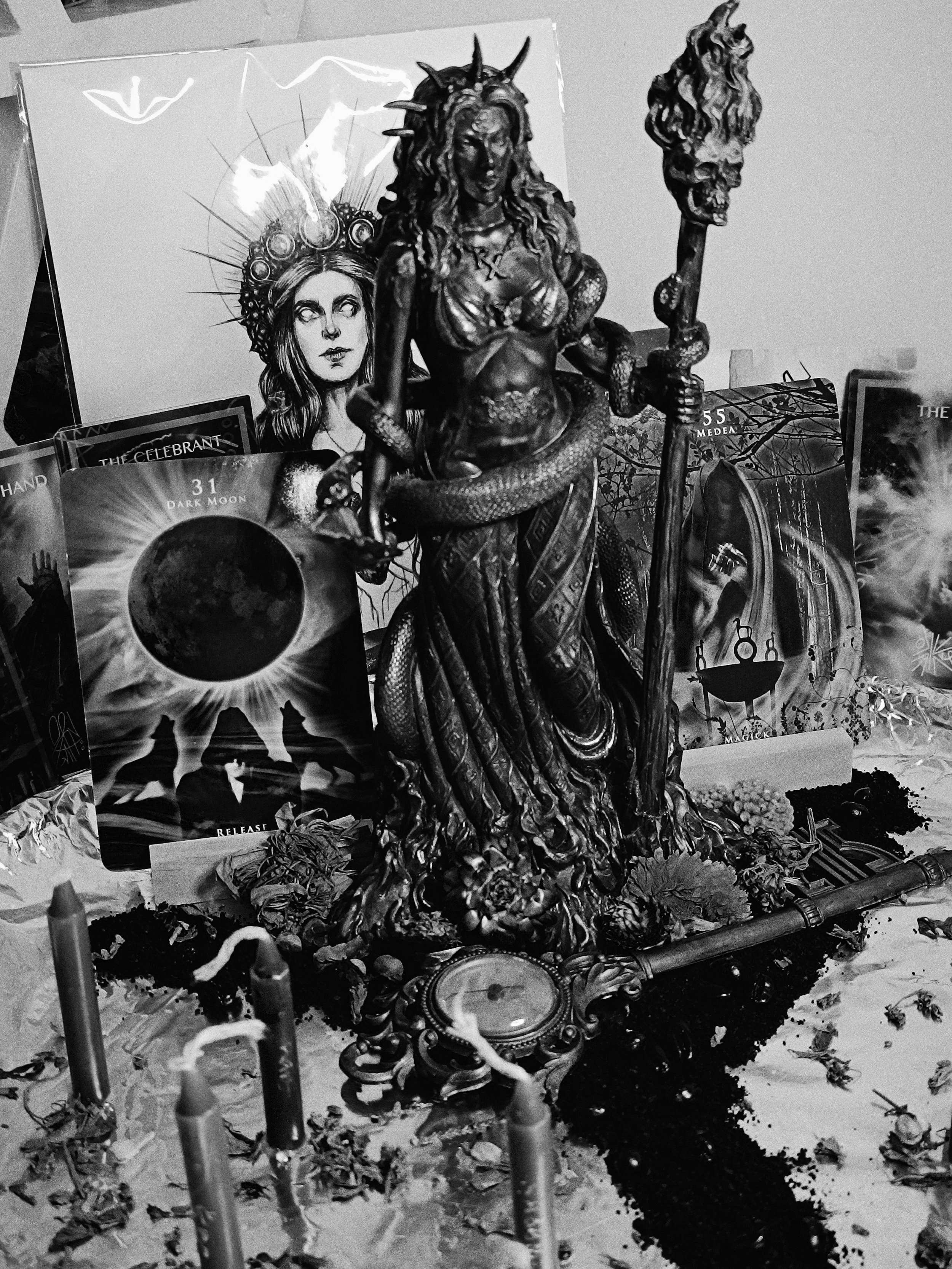 Black-and-white Hekate altar with candles, books, and ritual objects.
