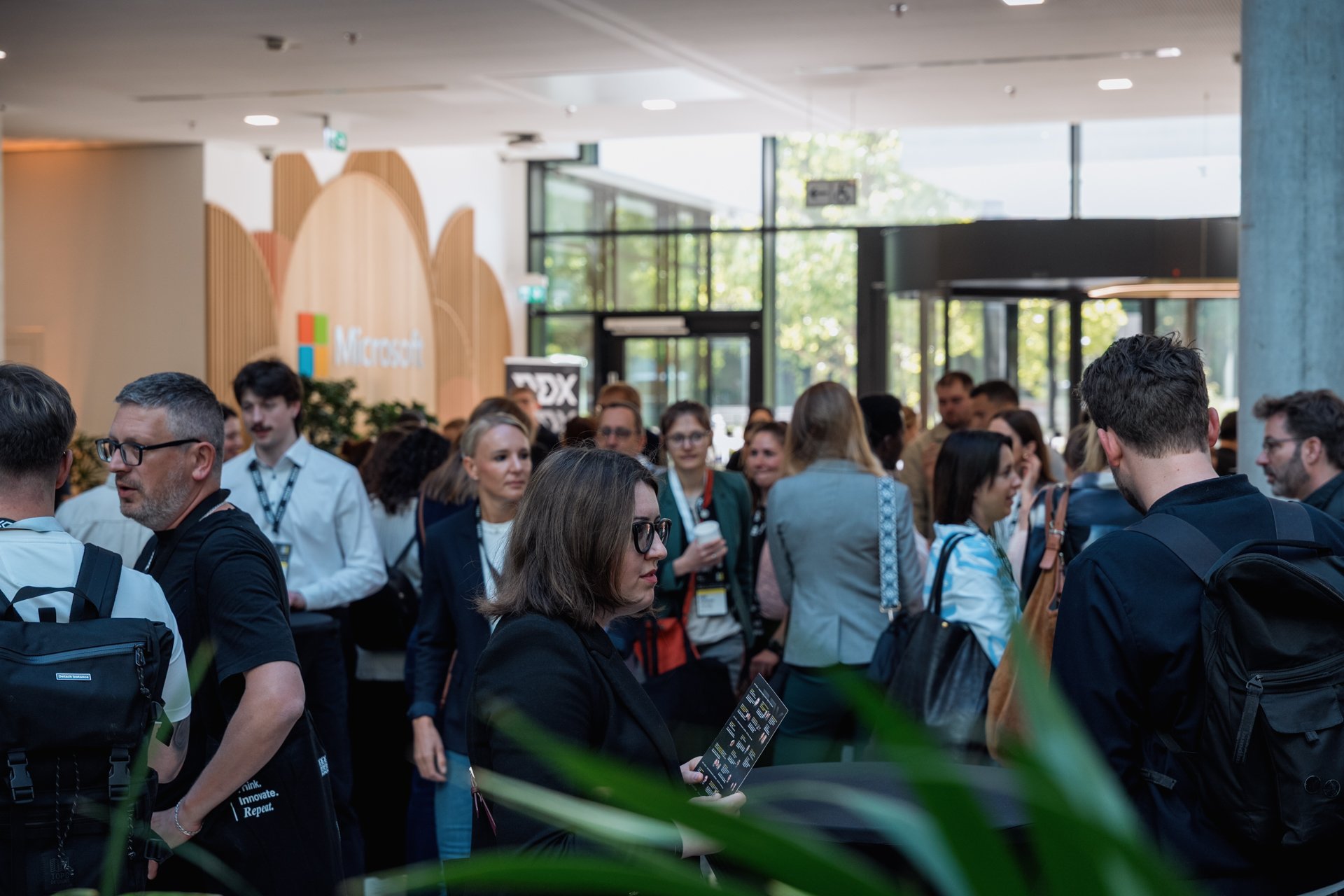A group of people at a Microsoft event in a modern lobby with large glass windows and the Microsoft logo visible.