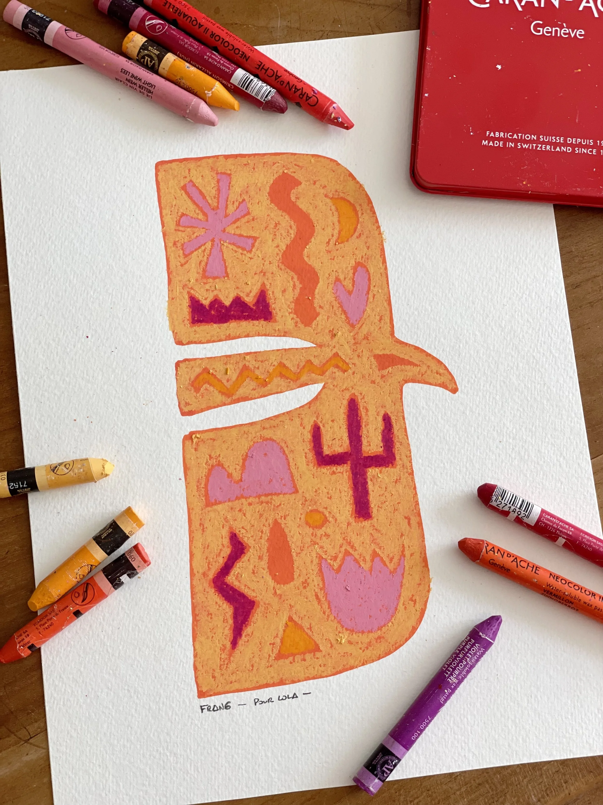 A colorful drawing of a pumpkin with various decorative symbols inside it, created with orange, pink, purple, and yellow markers, with additional markers lying around on white textured paper and a wooden surface.