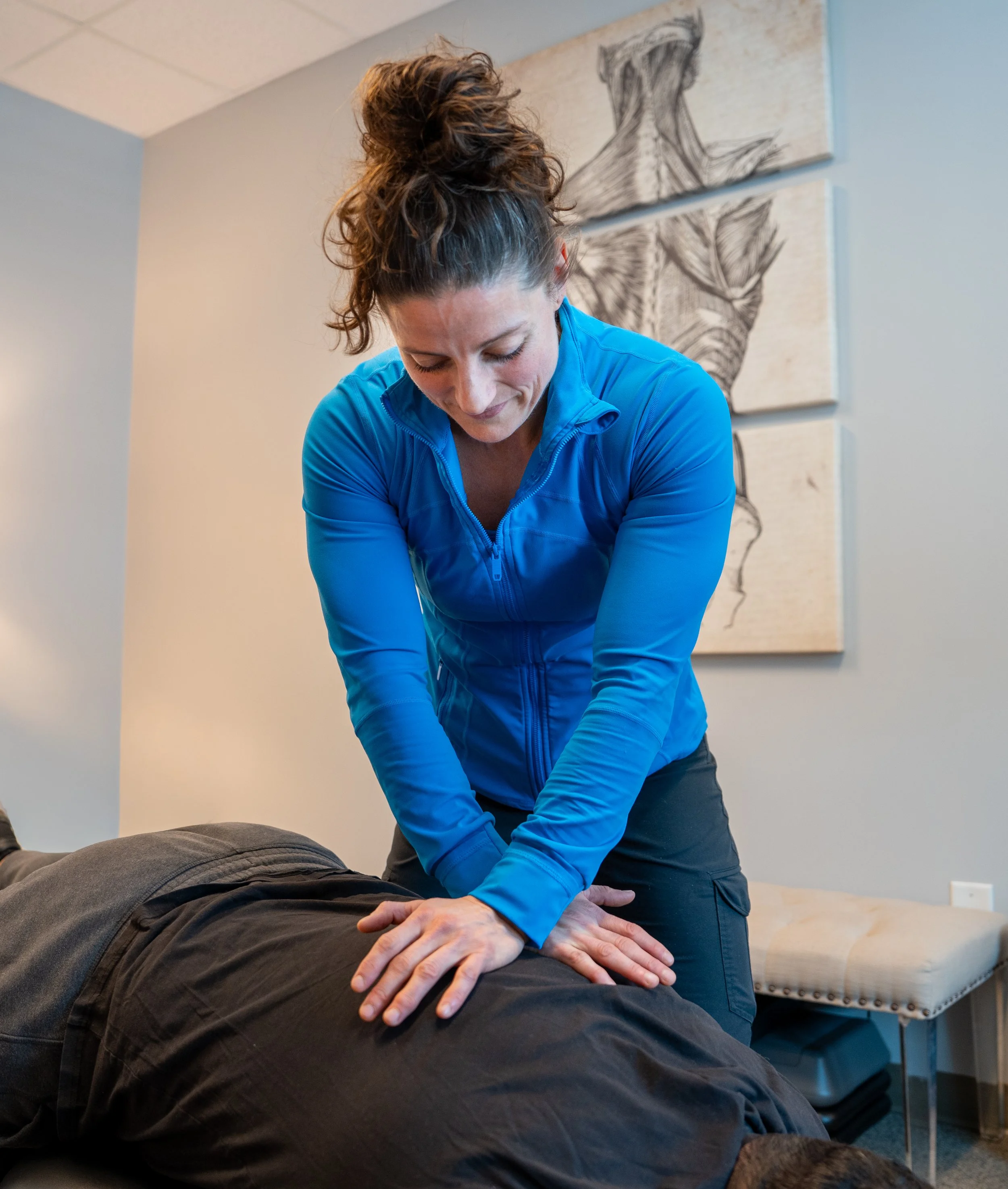 A person receiving a chiropractic adjustment or massage from a healthcare professional, who is applying pressure with her hands on the person's back.