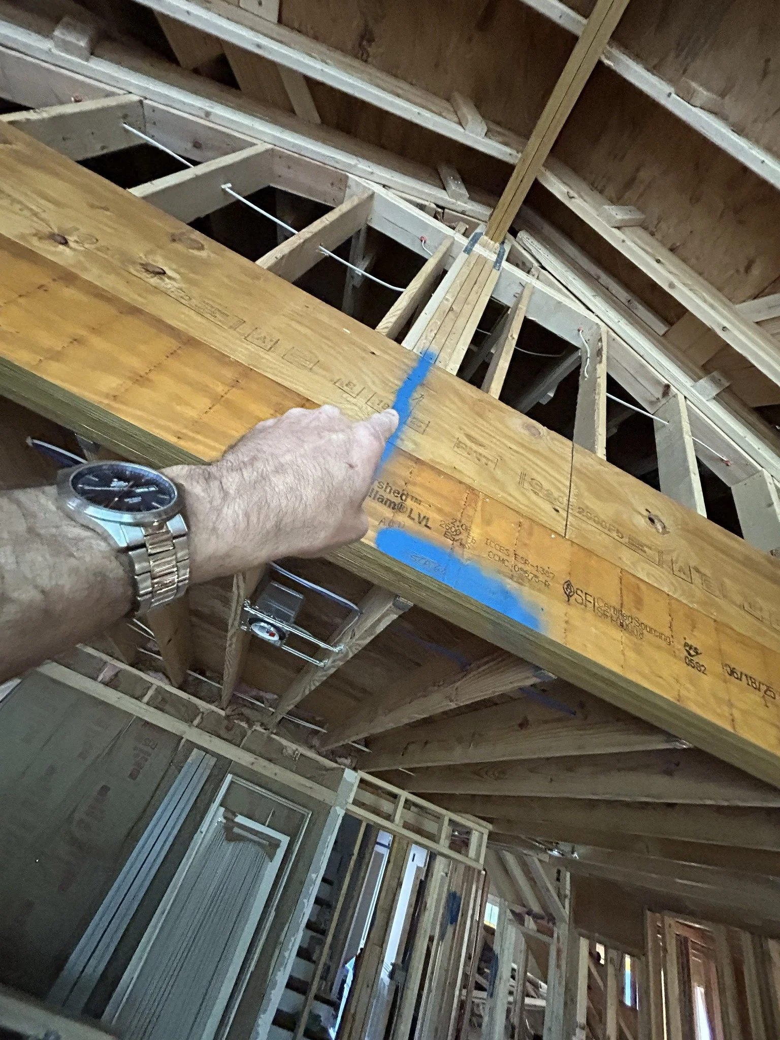 Construction site showing wooden framing for walls and ceiling in a building under construction.