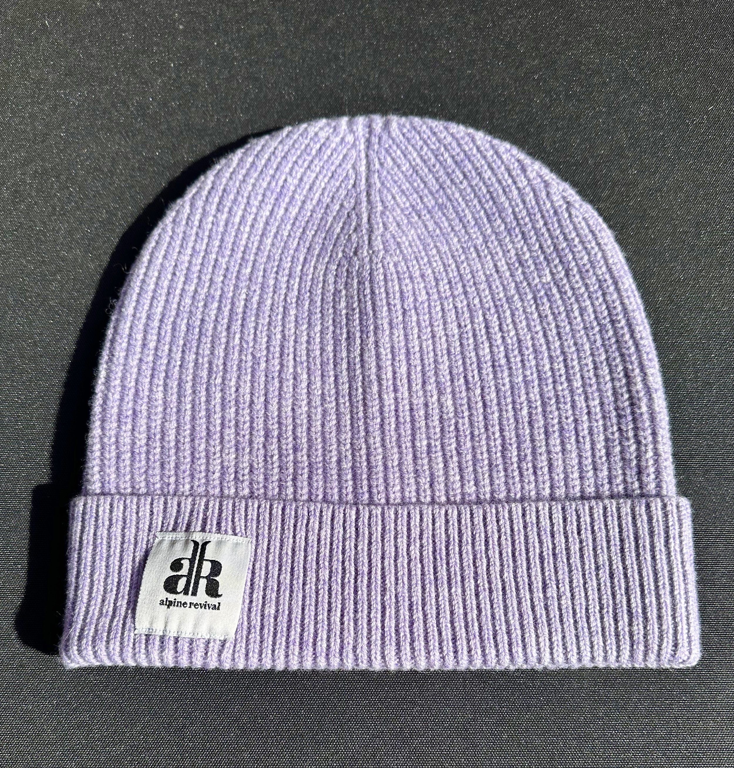 A cashmere-wool mix beanie laying on a table in the color lavender (Copy)