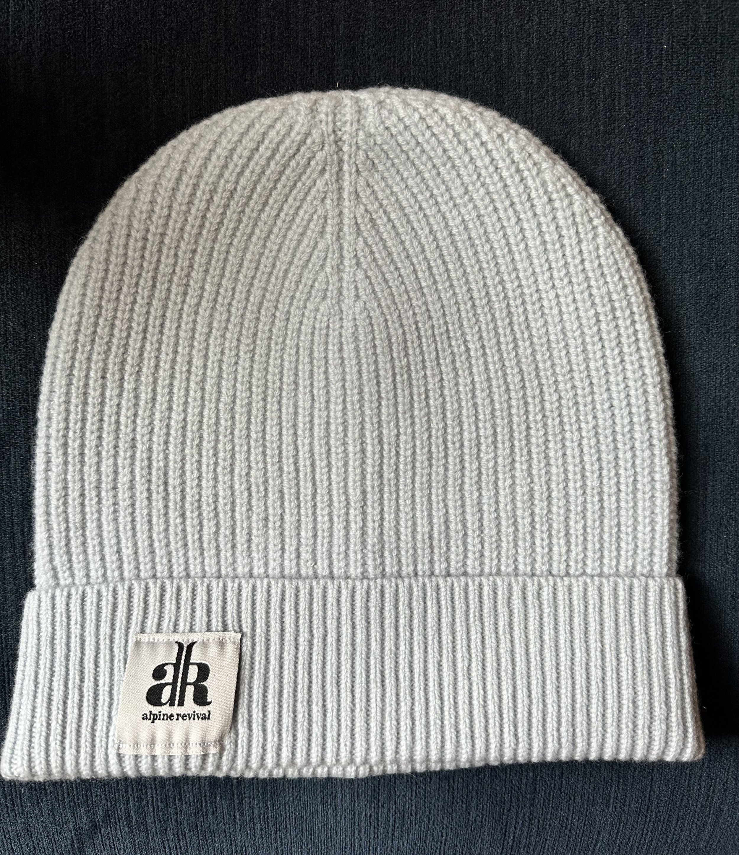 A cashmere-wool mix beanie laying on a table in the color light grey
