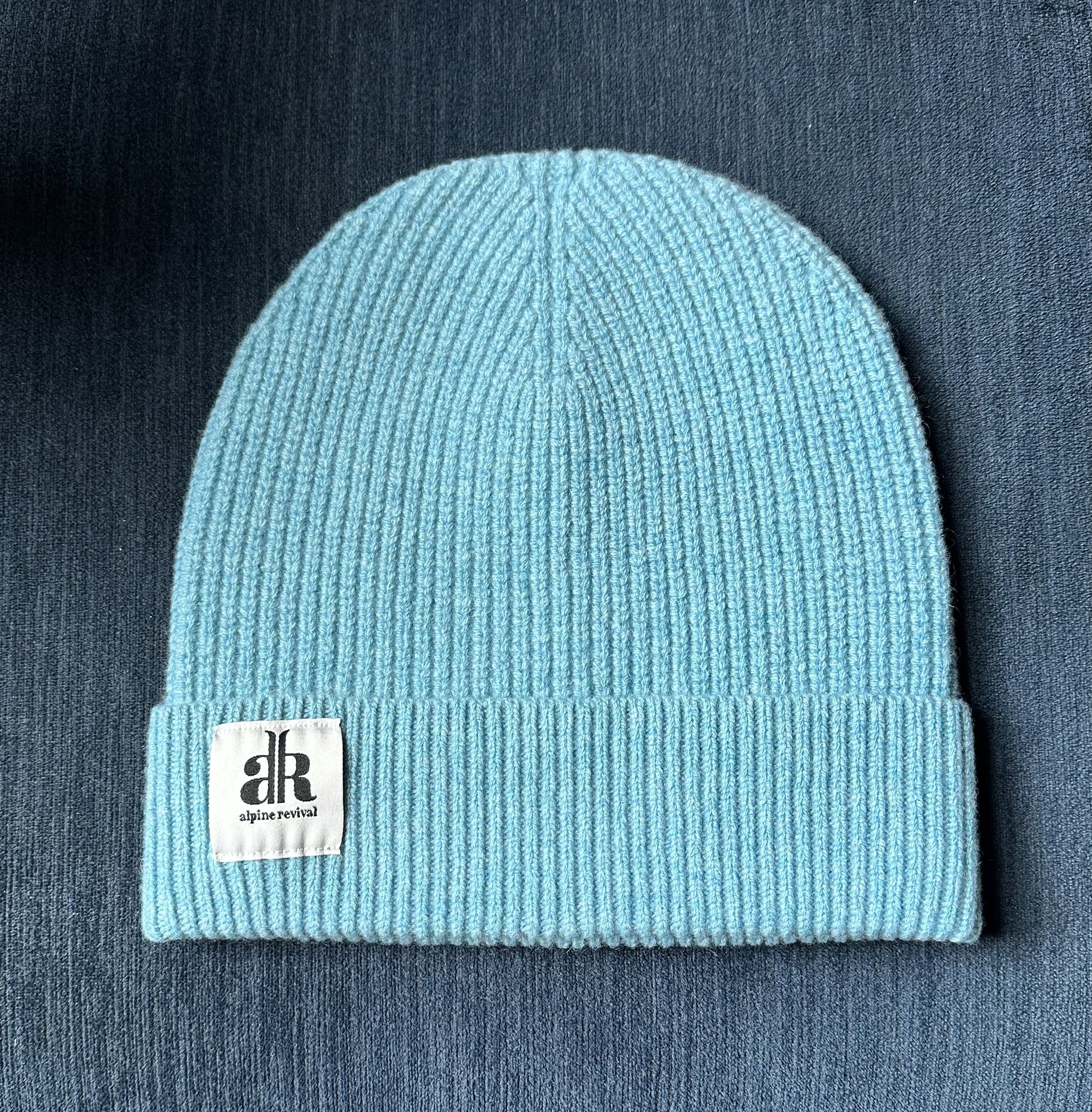 A cashmere-wool mix beanie laying on a table in the color aqua blue