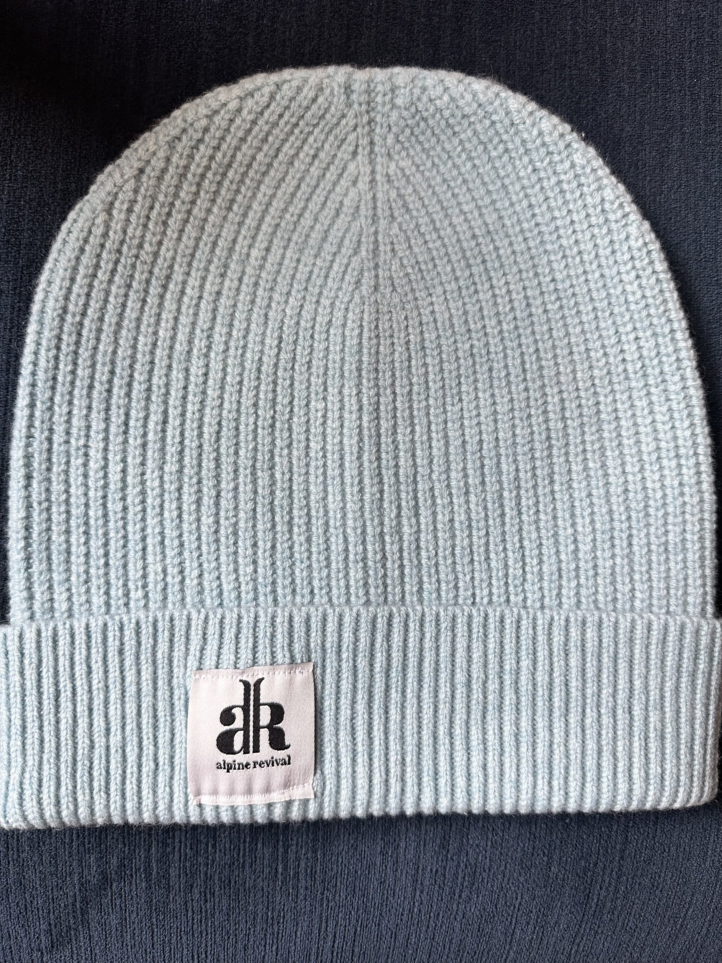 A cashmere-wool mix beanie laying on a table in the color light grey