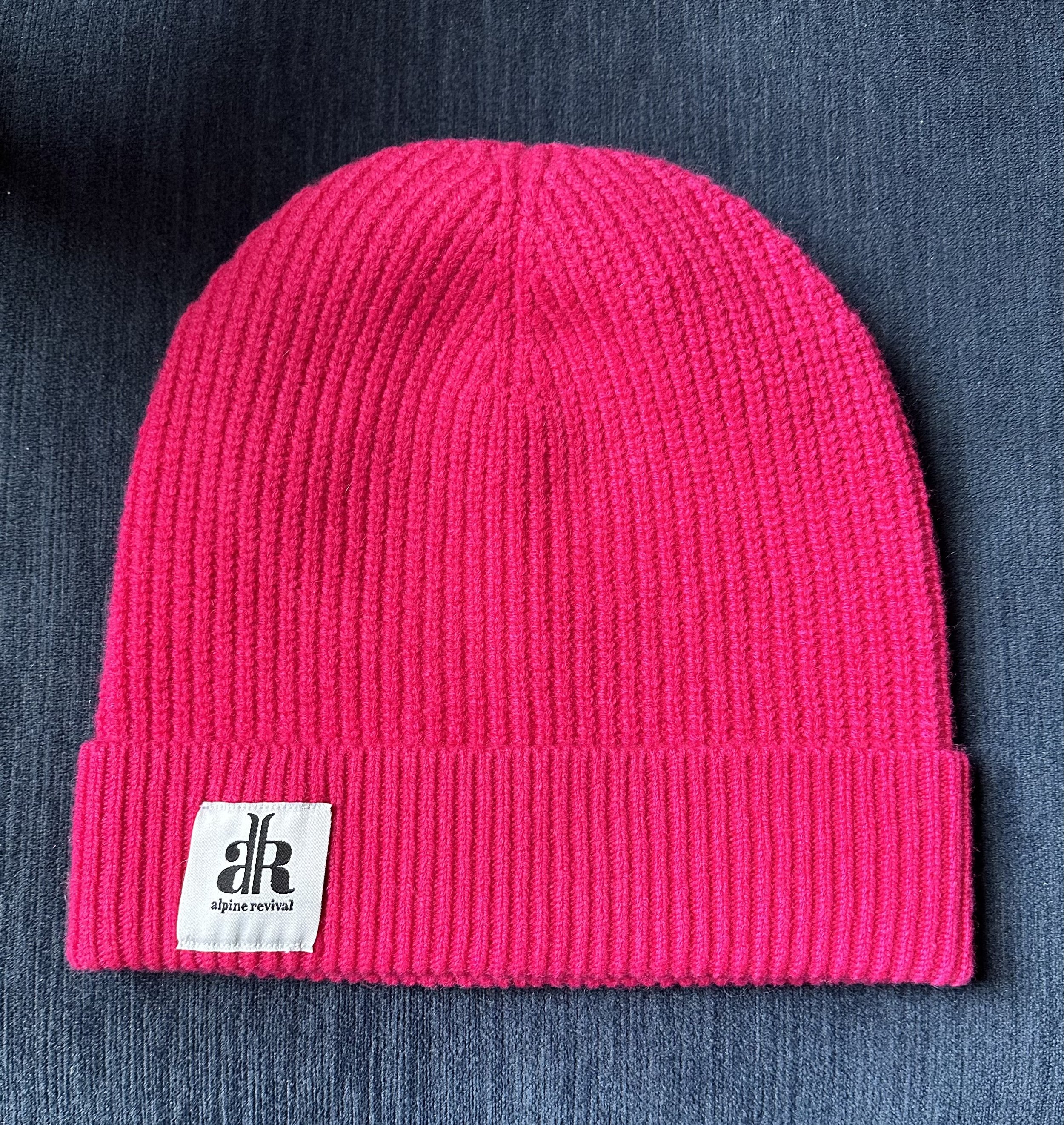 A cashmere-wool mix beanie laying on a table in the color bright pink (Copy)