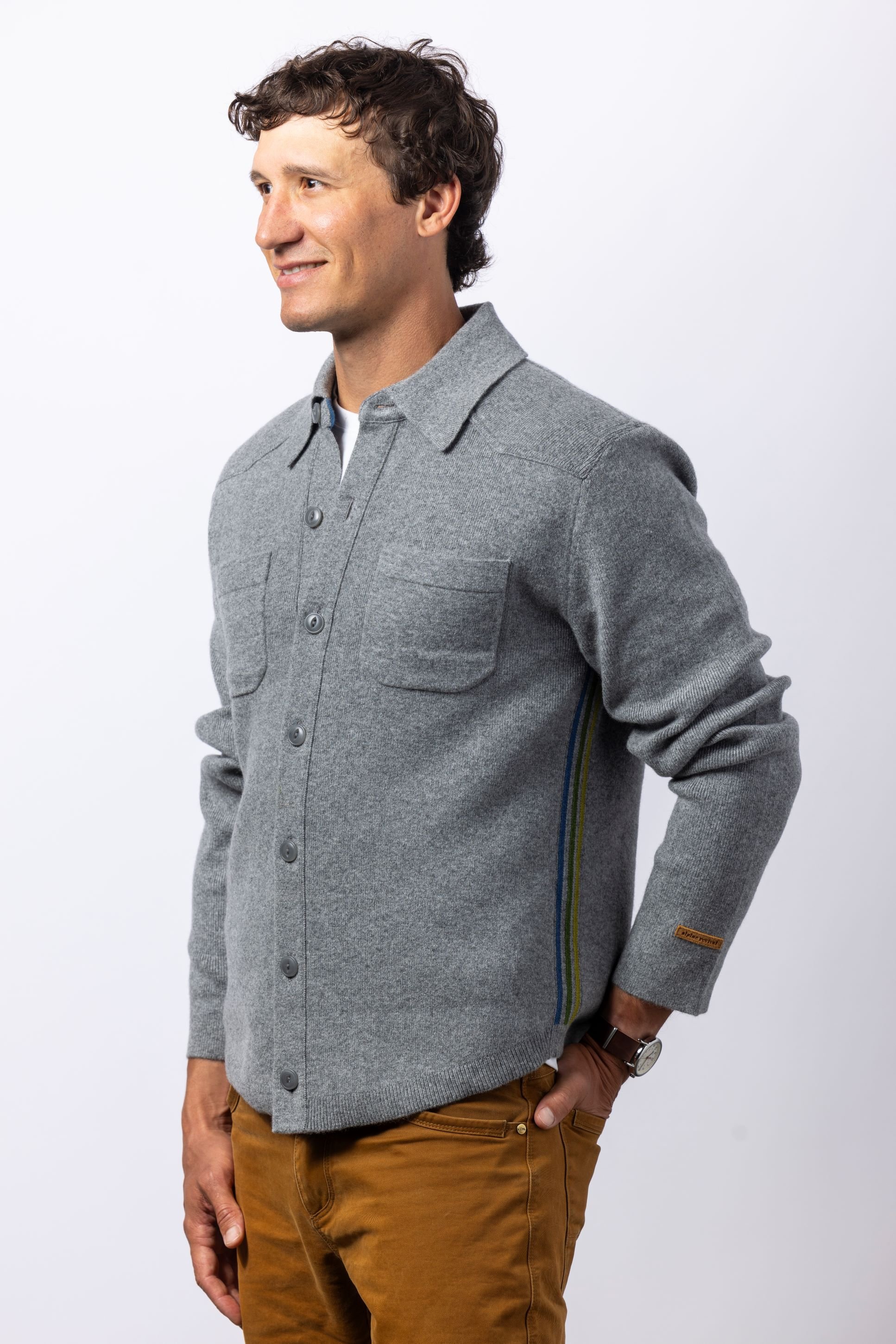 Man in a studio wearing a grey button down flannel cashmere shirt facing left