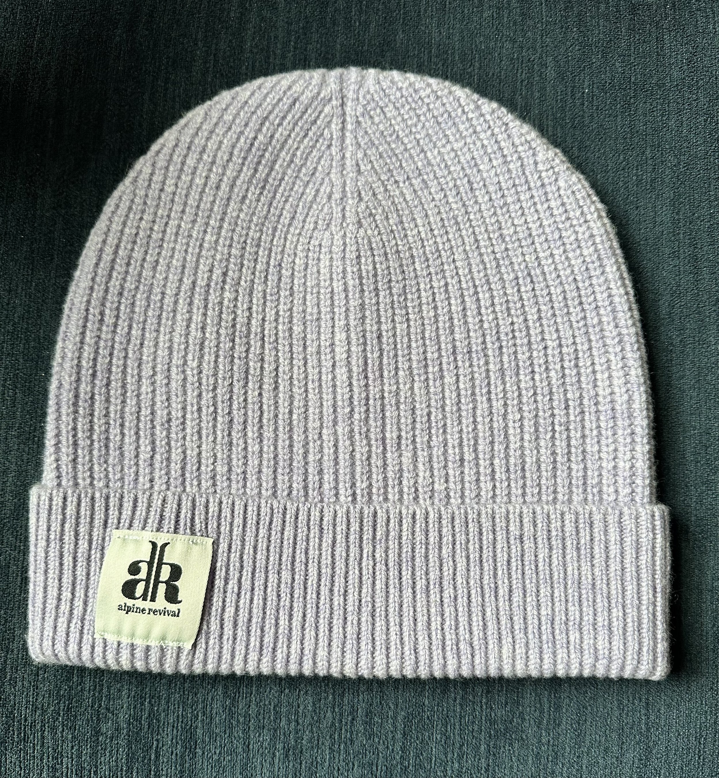 A cashmere-wool mix beanie laying on a table in the color light grey