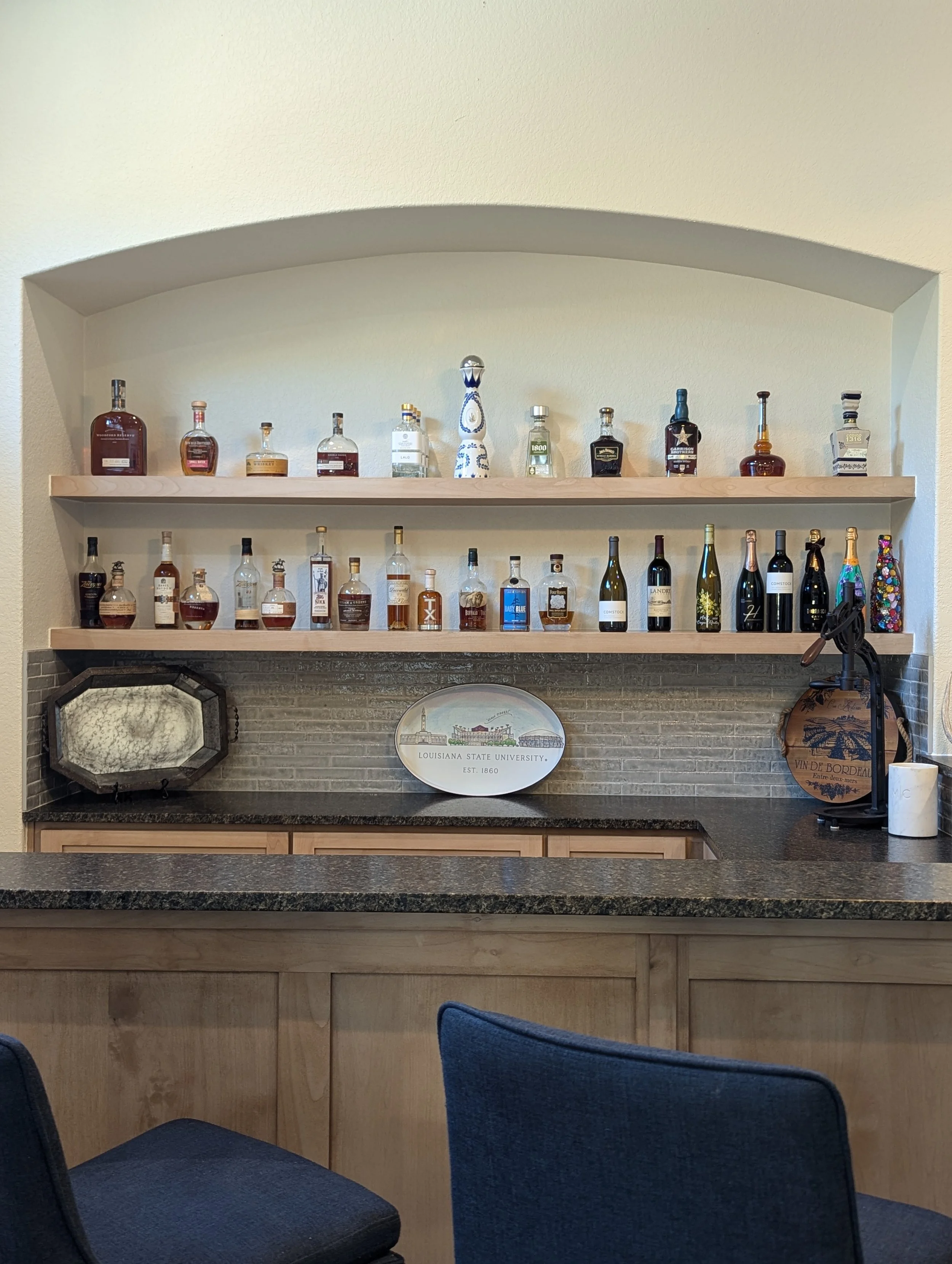 a home bar with many different types of alcohol organized and displayed on a shelving unit