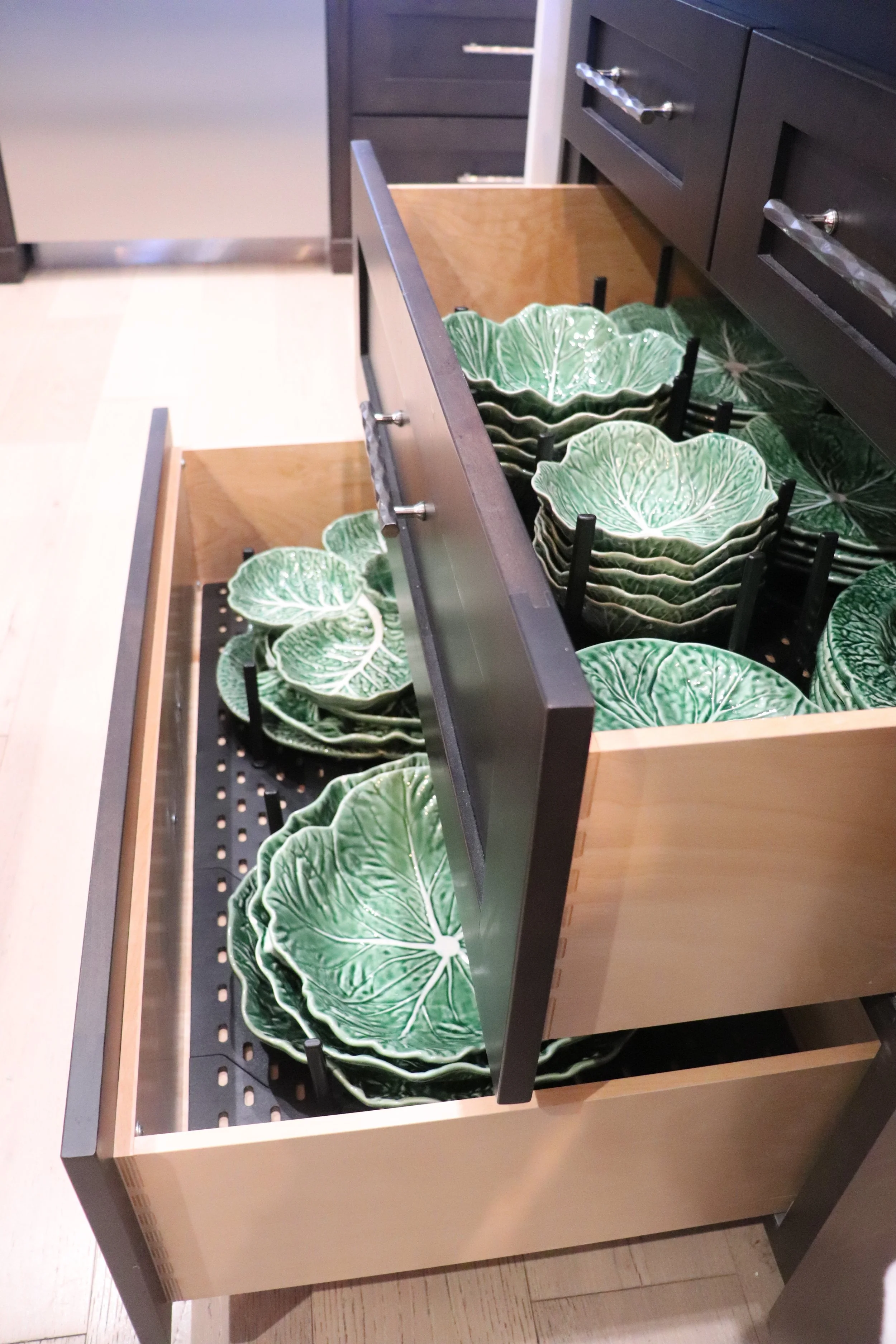 two kitchen drawers opened staggery with lettuce shaped plates that are in the drawers with a plate organizer system installed 