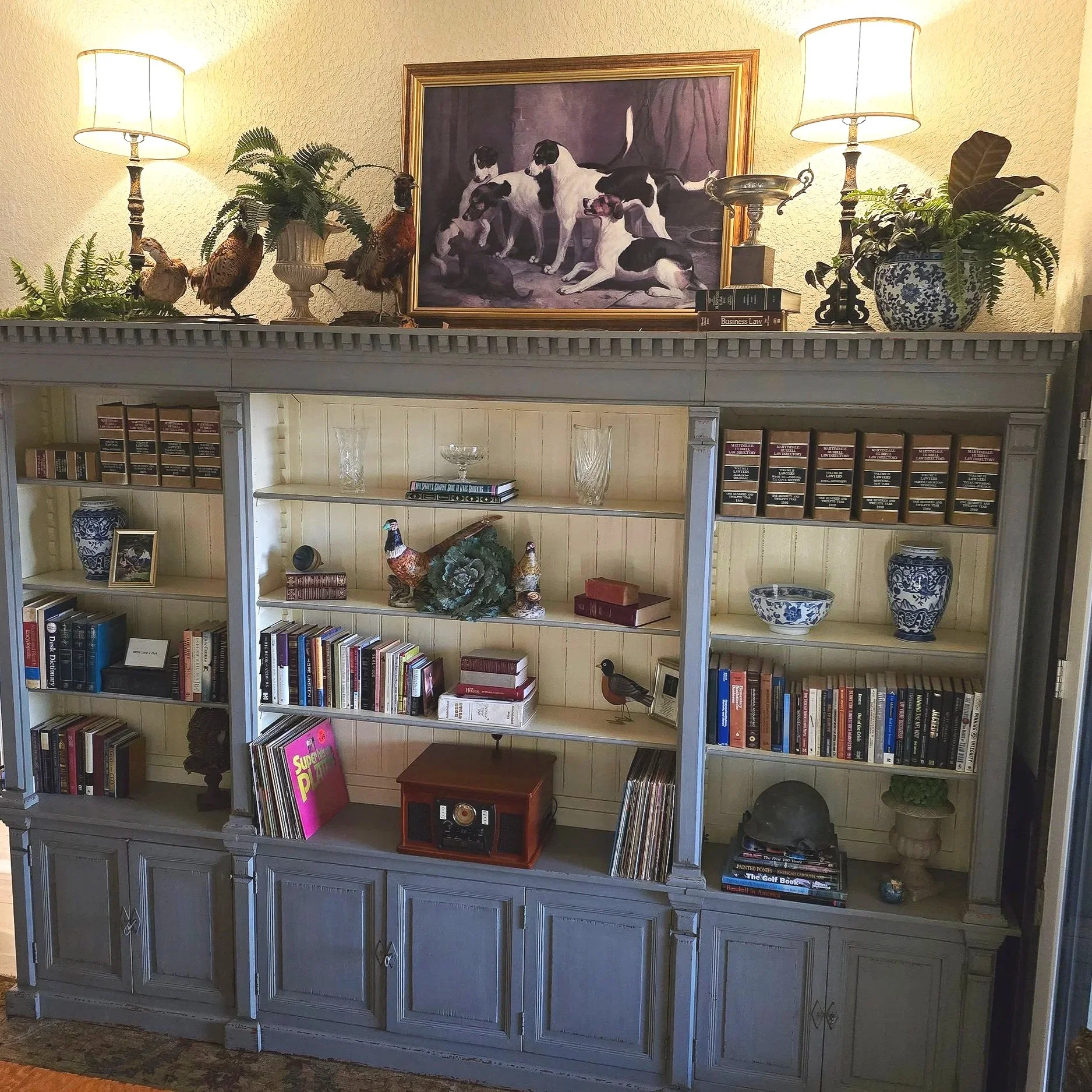 an open armoire that displays books and taxidermy pheasants and a record player