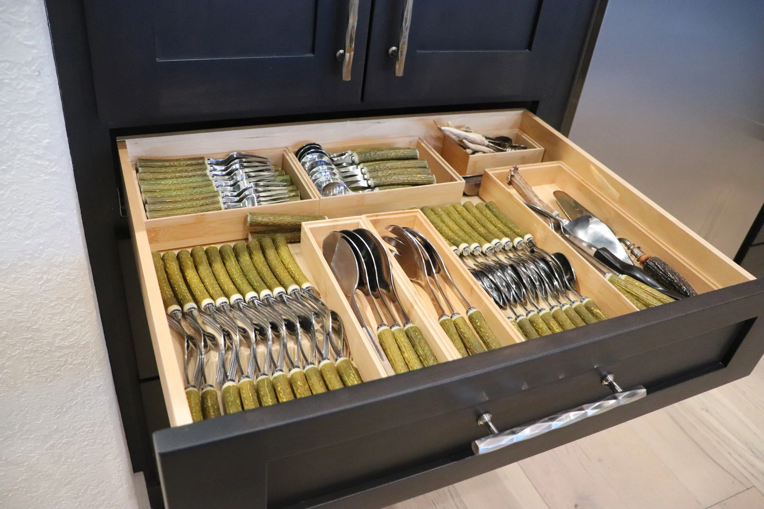 an silverware drawer that has an organizer system in it with antler handled silverware laying neatly in the drawer