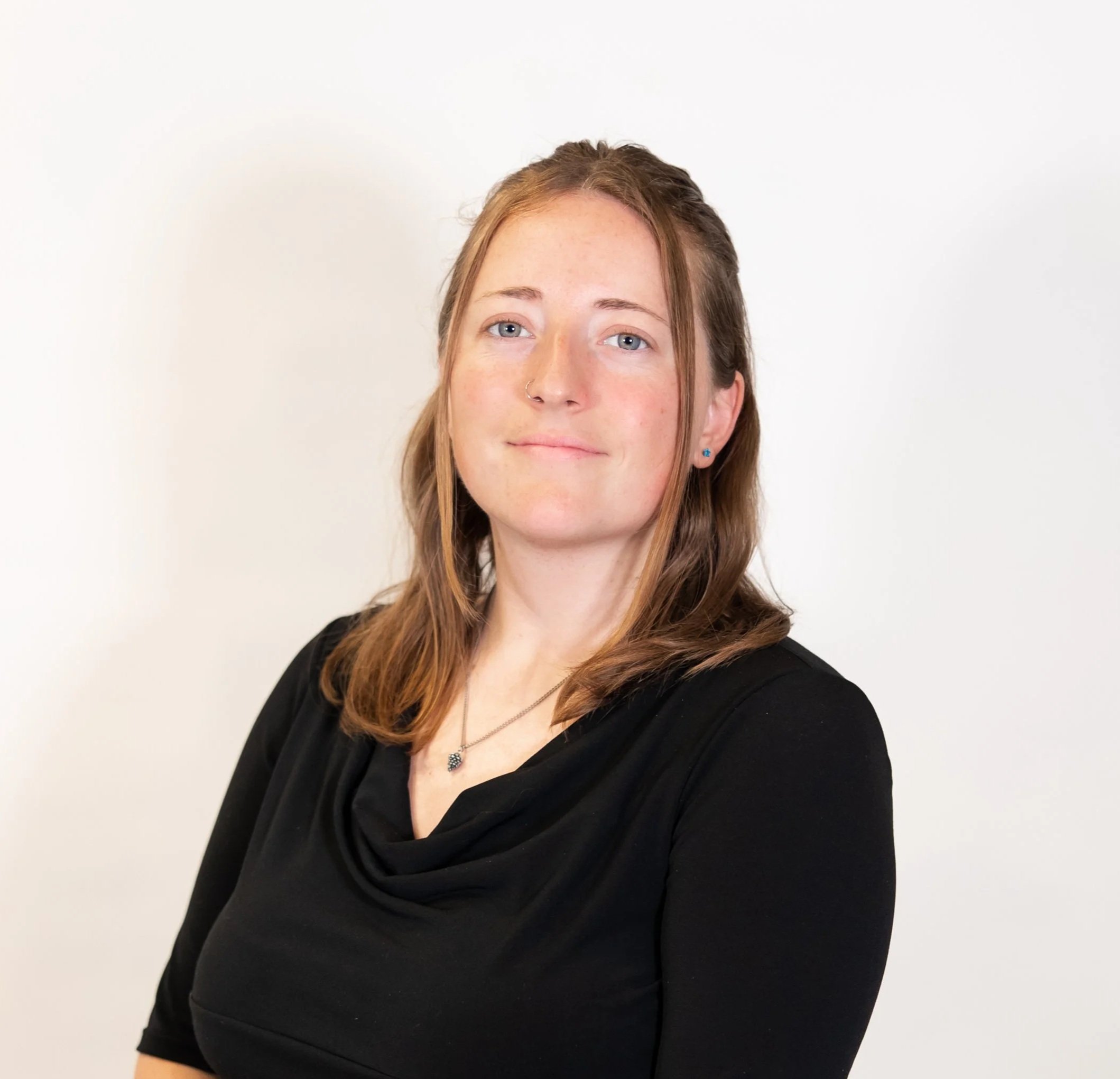 woman wearing black has her hands folder in front of her smiling