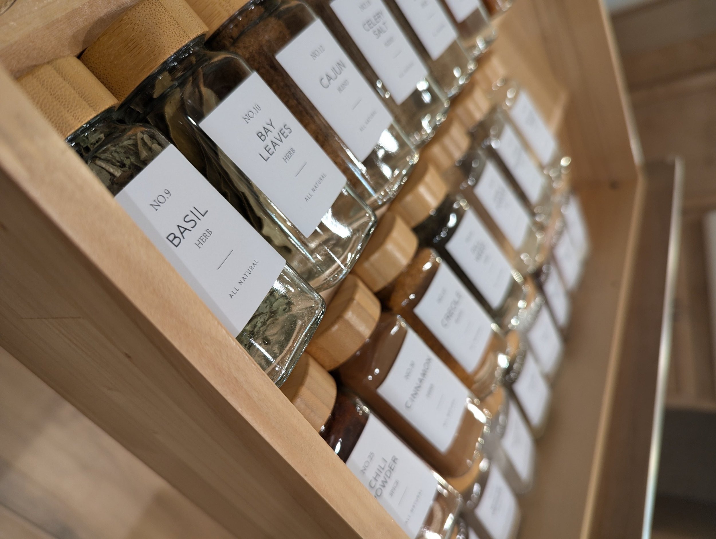 Labeled bamboo seasoning jars in a drawer
