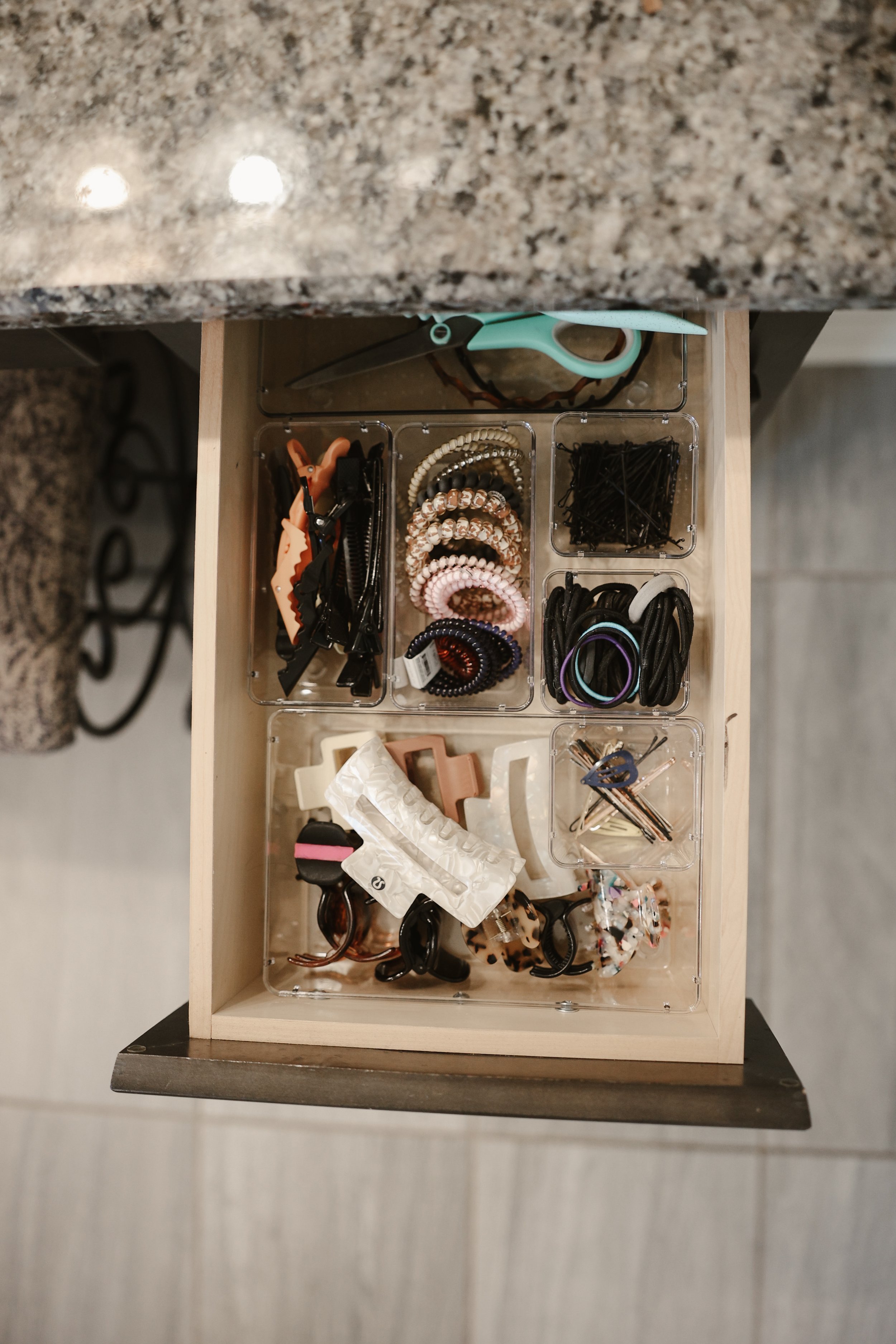 a bathroom drawer with drawer organizers that hold hair ties, hair clips, pins.