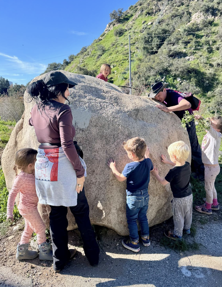 Teachers and kids climbing a bolder.