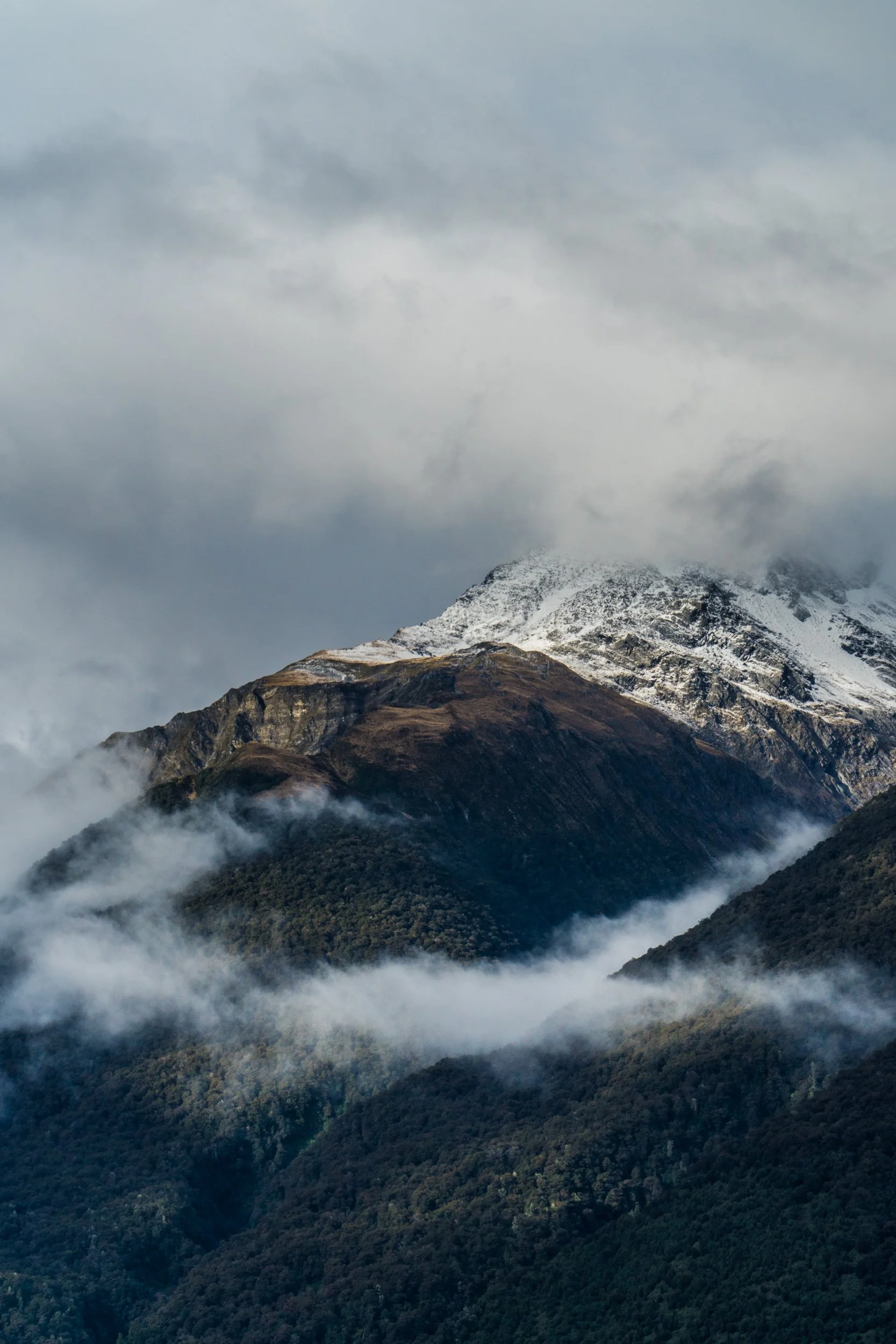 Snow-capped mountains with clouds and fog surrounding the slopes.