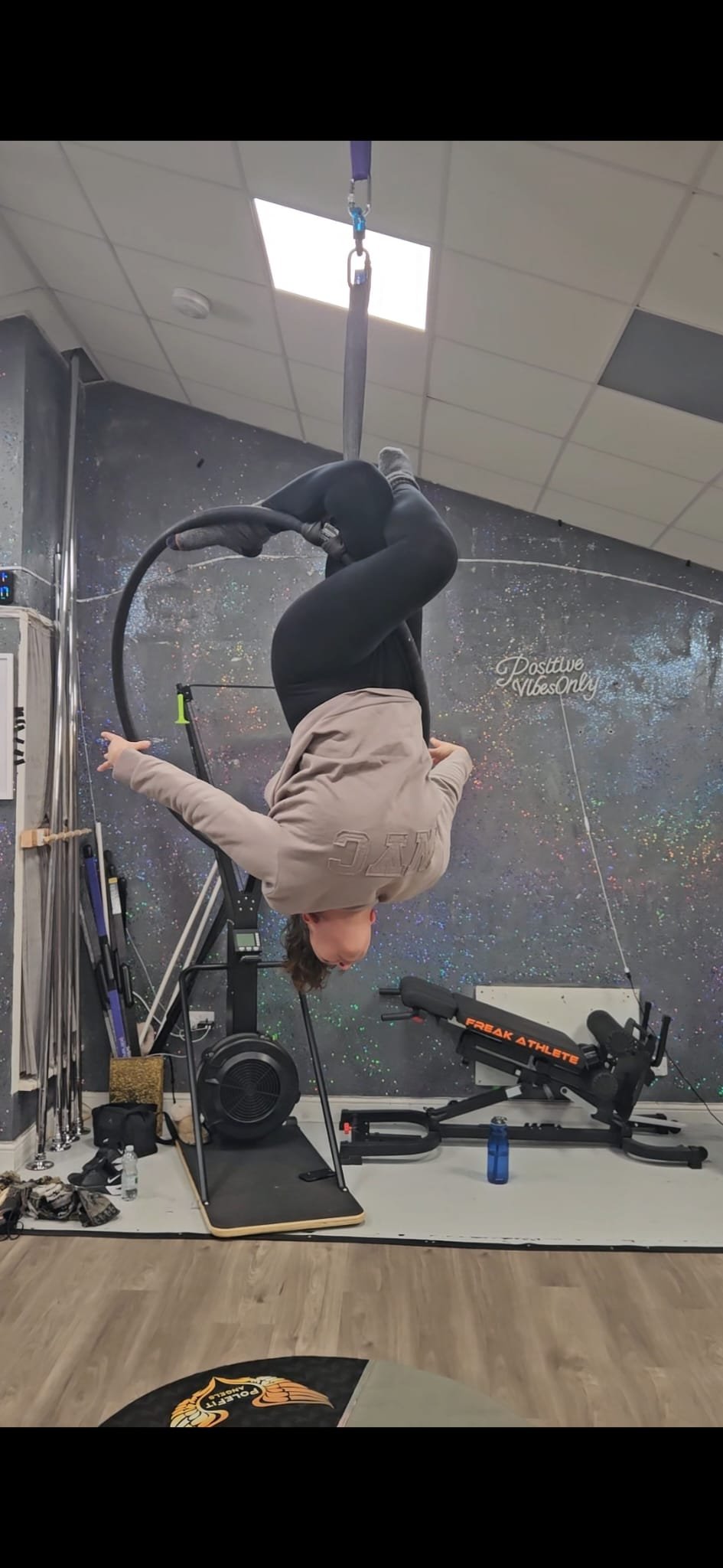 lady hanging off top bar of a hoop