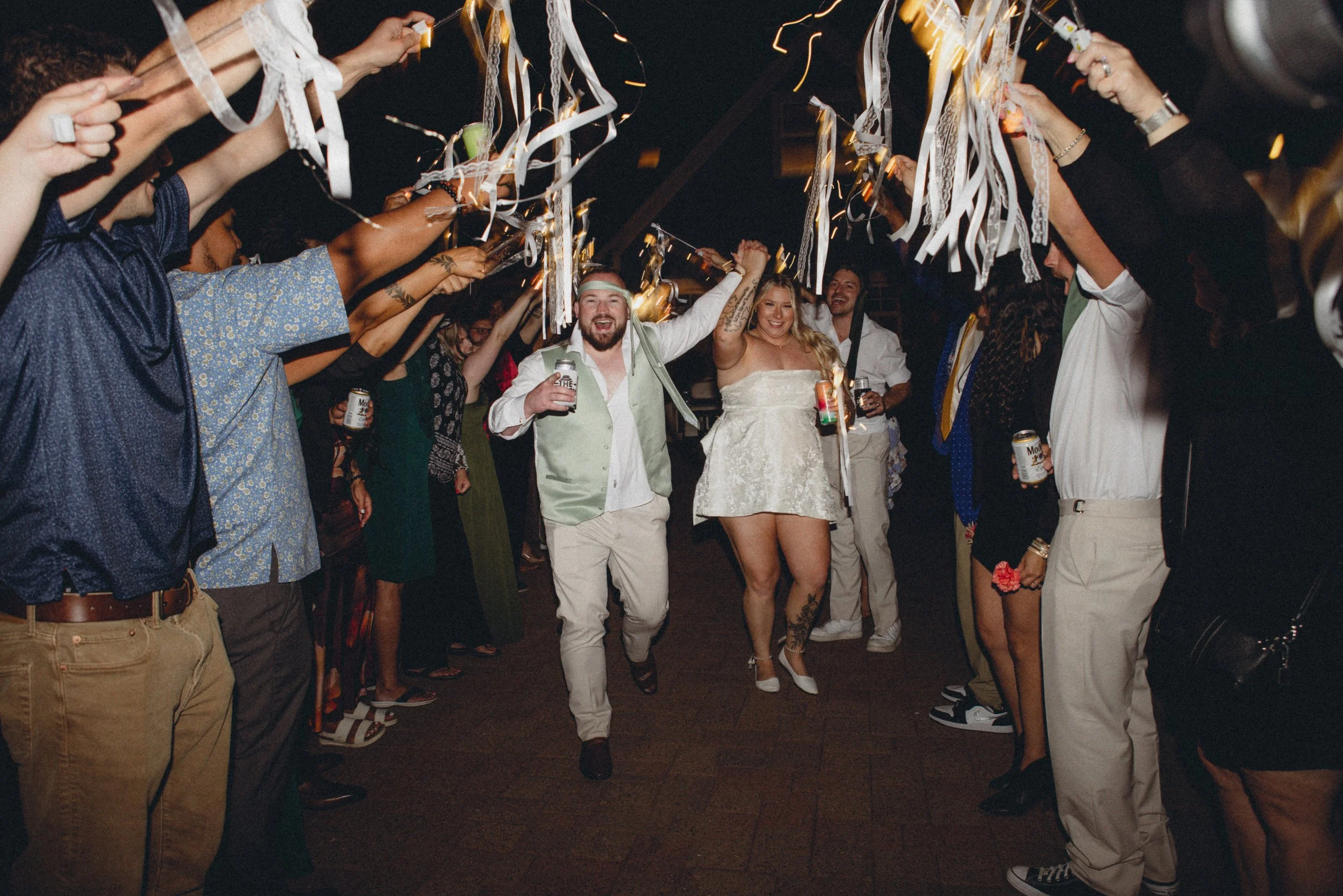 People celebrating at a party with streamers and holding drinks, dancing and smiling.