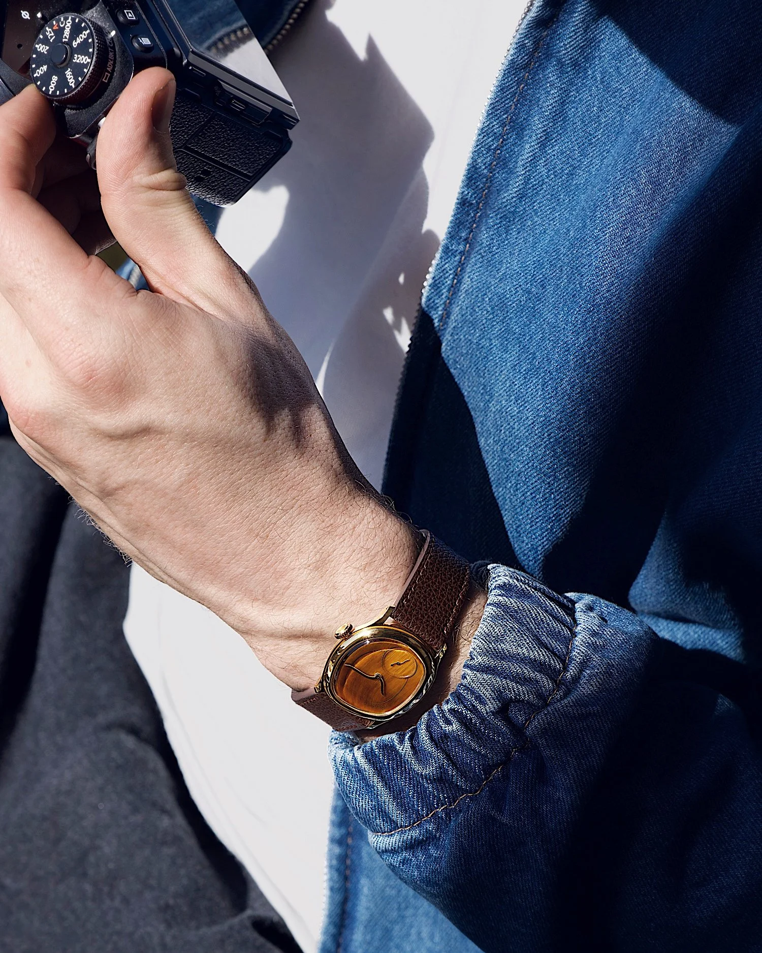 &bull; Mirage Tiger Eye
A souvenir from GWD 2025, of our dear friend Tim Vaux reviewing his shots with a Tiger Eye on his wrist. We often tell collectors that the stone dials are something else in direct sunlight, and this stolen shot illustrates tha