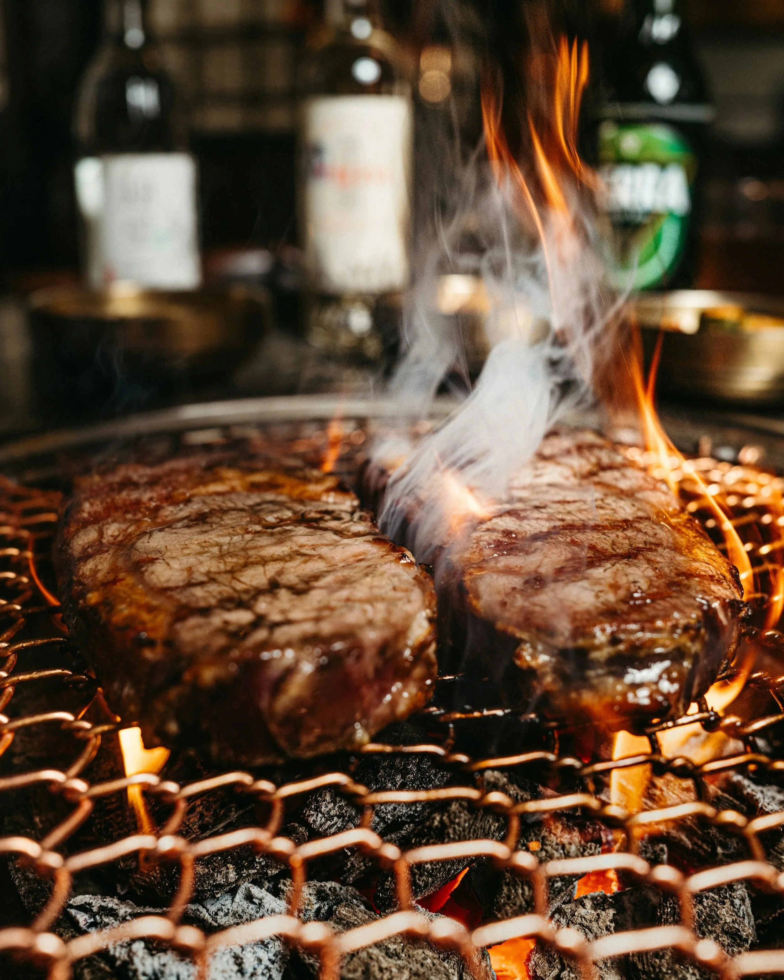Dos filetes de carne roja cocinándose a la parrilla. Un nuevo estudio analiza cómo un alimento clave en la evolución humana se ha convertido hoy en un factor asociado a enfermedades crónicas y al impacto ambiental de la ganadería.