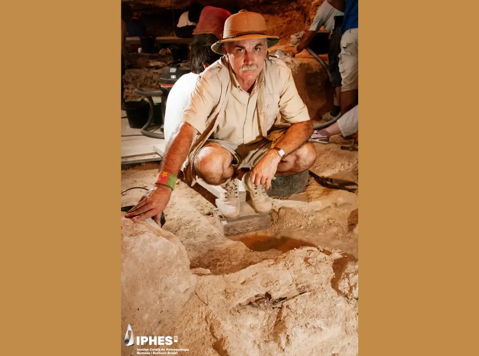 El arqueólogo Eudald Carbonell, impulsor de las excavaciones sistemáticas del Abric Romaní desde 1983, posa junto al objeto de madera interpretado como una maza neandertal.