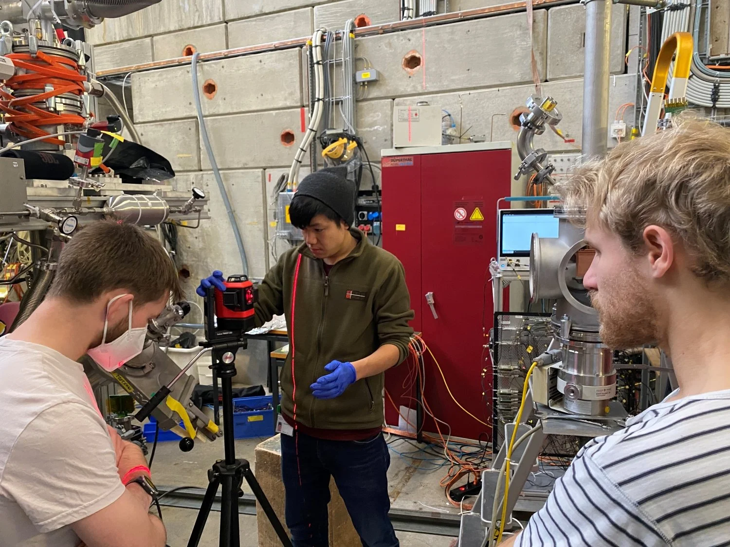 Los doctorandos Robert Waddy, Jesse Zhang y Paul Wegmann, de izquierda a derecha, calibran el experimento con la línea de haz del Instituto Paul Scherrer.