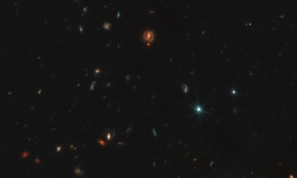 Los pequeños puntos rojos del cosmos son agujeros negros jóvenes, envueltos en densos capullos de gas que están devorando para crecer. El intenso calor generado en este proceso hace que brillen con su característico color rojo.