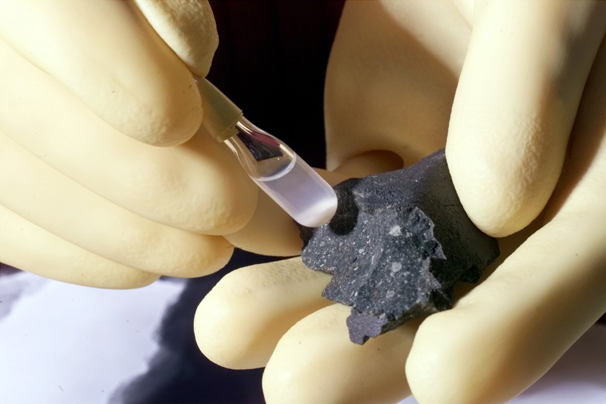Fragmento del meteorito Murchison (derecha) y partículas aisladas de su material, conservadas en un tubo de ensayo.