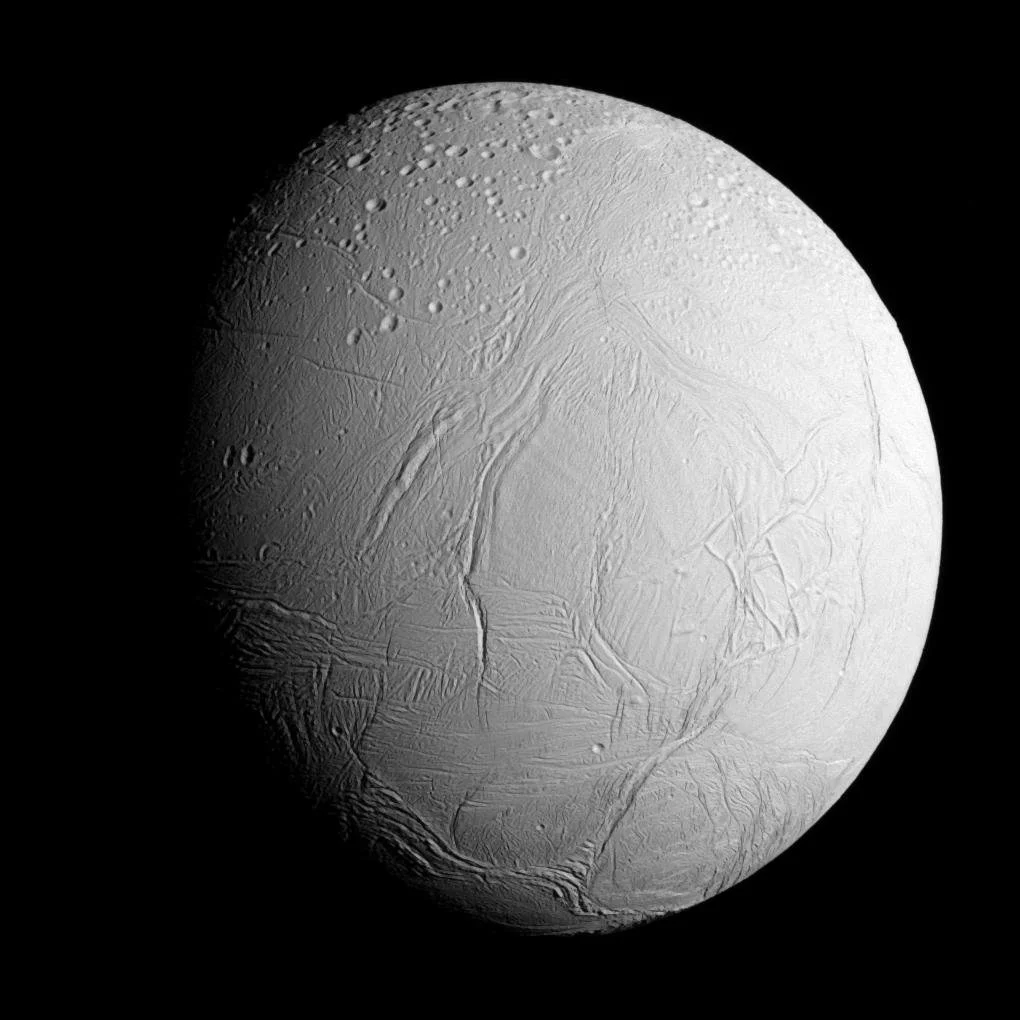 Encélado, una de las lunas heladas de Saturno, fotografiada por la sonda Cassini durante uno de sus sobrevuelos más cercanos. Bajo su corteza de hielo se esconde un océano global que expulsa chorros de agua, vapor y compuestos orgánicos al es