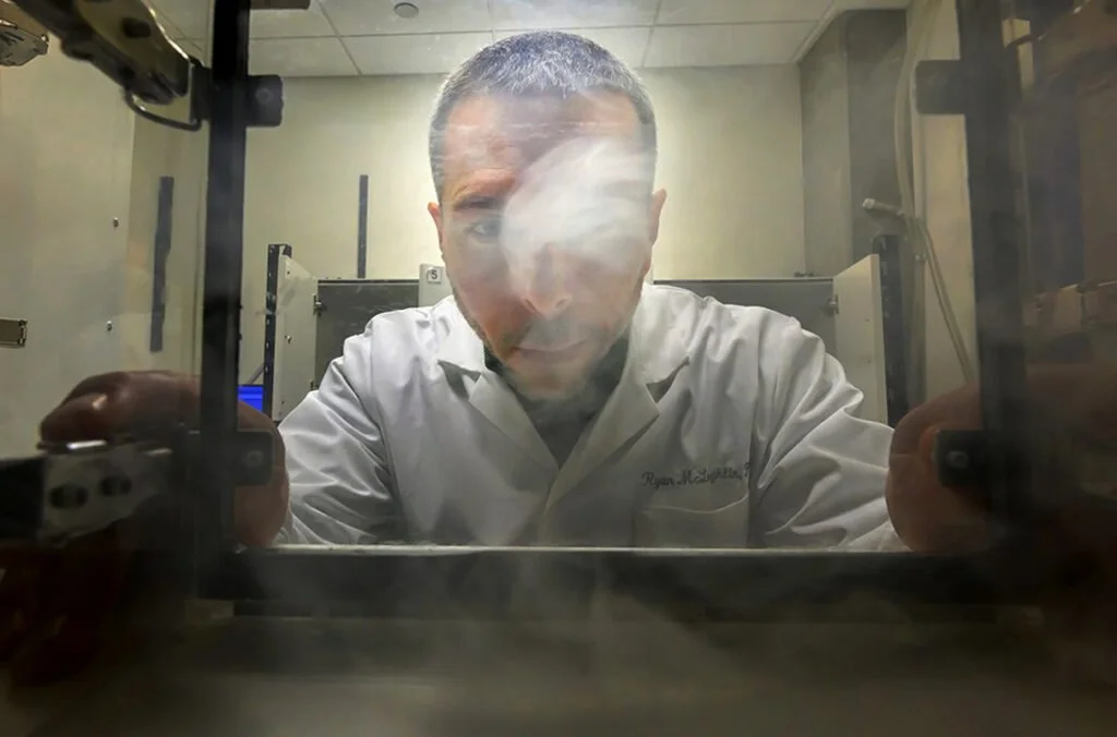 Ryan McLaughlin, profesor del Departamento de Fisiología Integrativa y Neurociencia de la Washington State University, observa una cámara transparente utilizada en experimentos de autoadministración de vapor de cannabis con ratas
